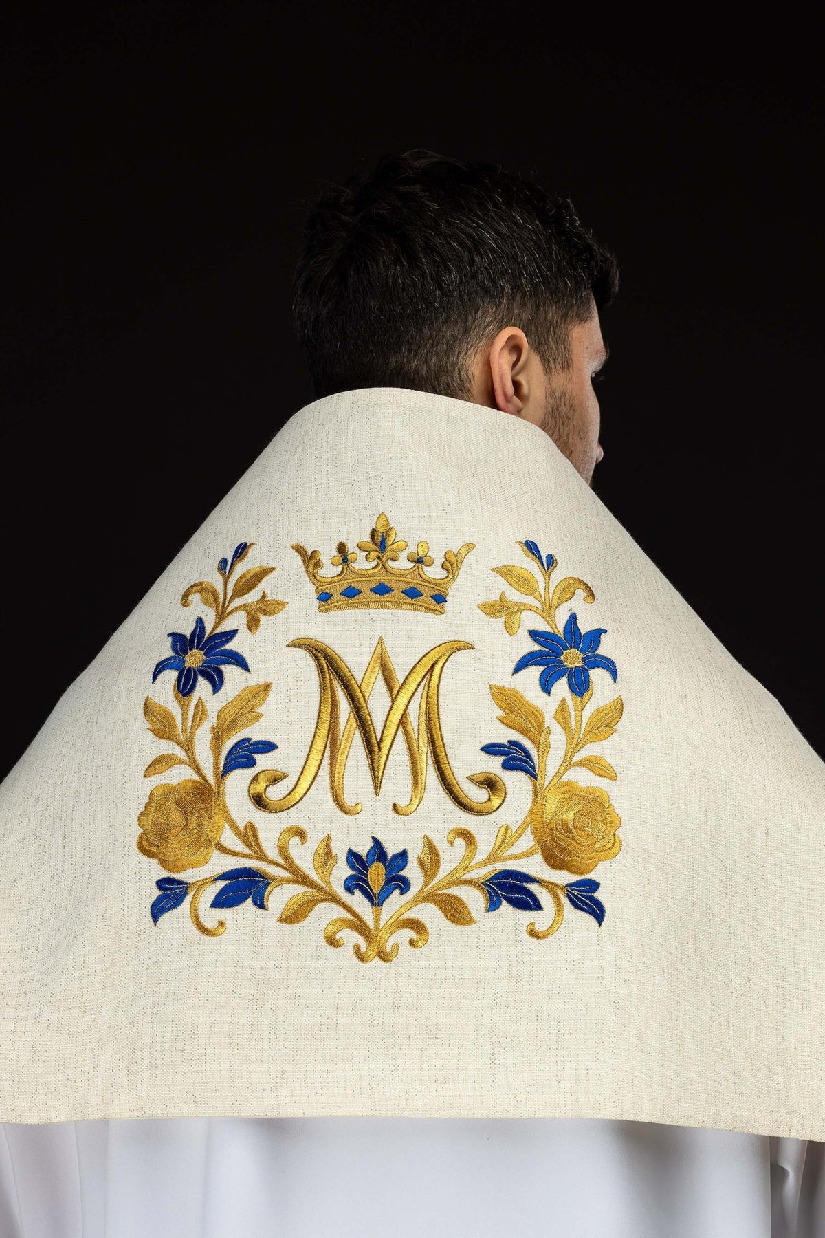 Véu umeral pelas costas, mostrando o monograma mariano cercado por flores e coroa