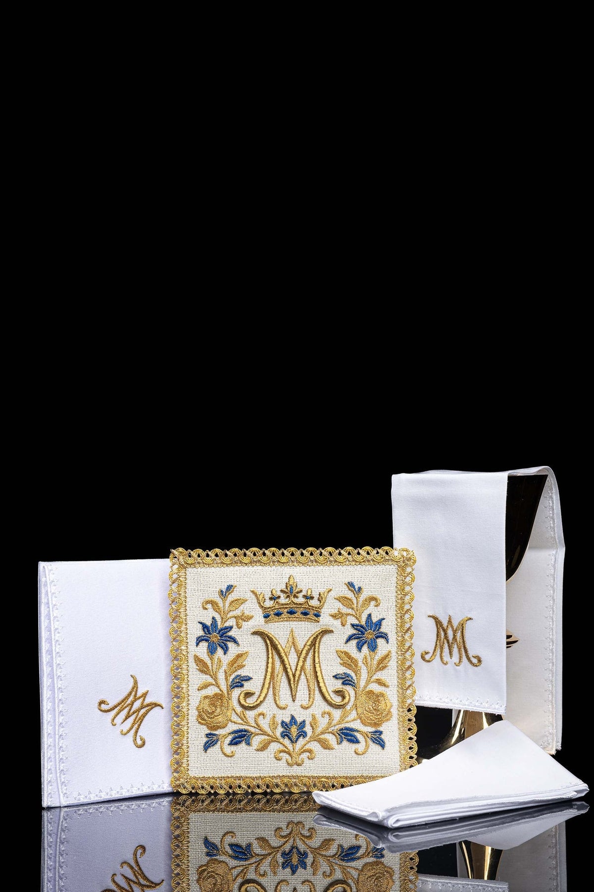 Conjunto de alfaias litúrgicas bordado com símbolo mariano, em branco e dourado, com detalhes azuis