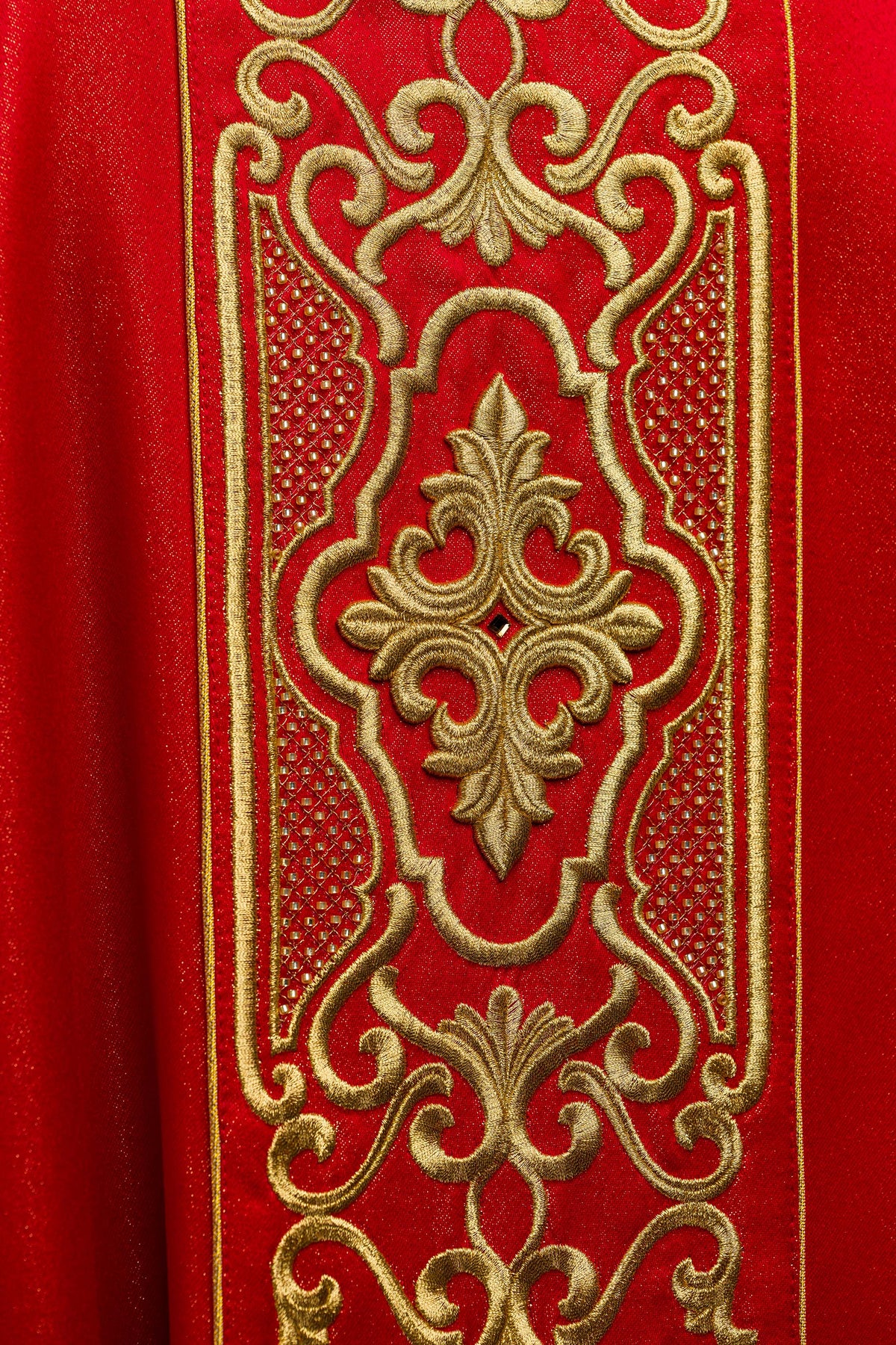 Casula vermelha com close-up do bordado dourado em arabescos e detalhes vazados