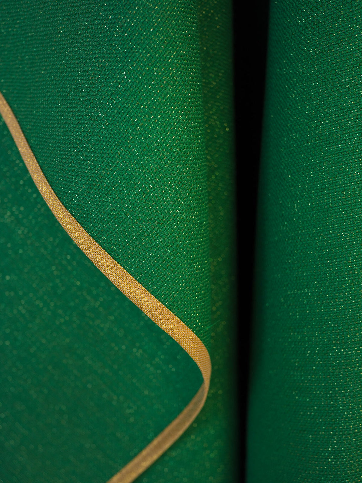 Casula verde em close-up, mostrando o tecido e o viés dourado da borda