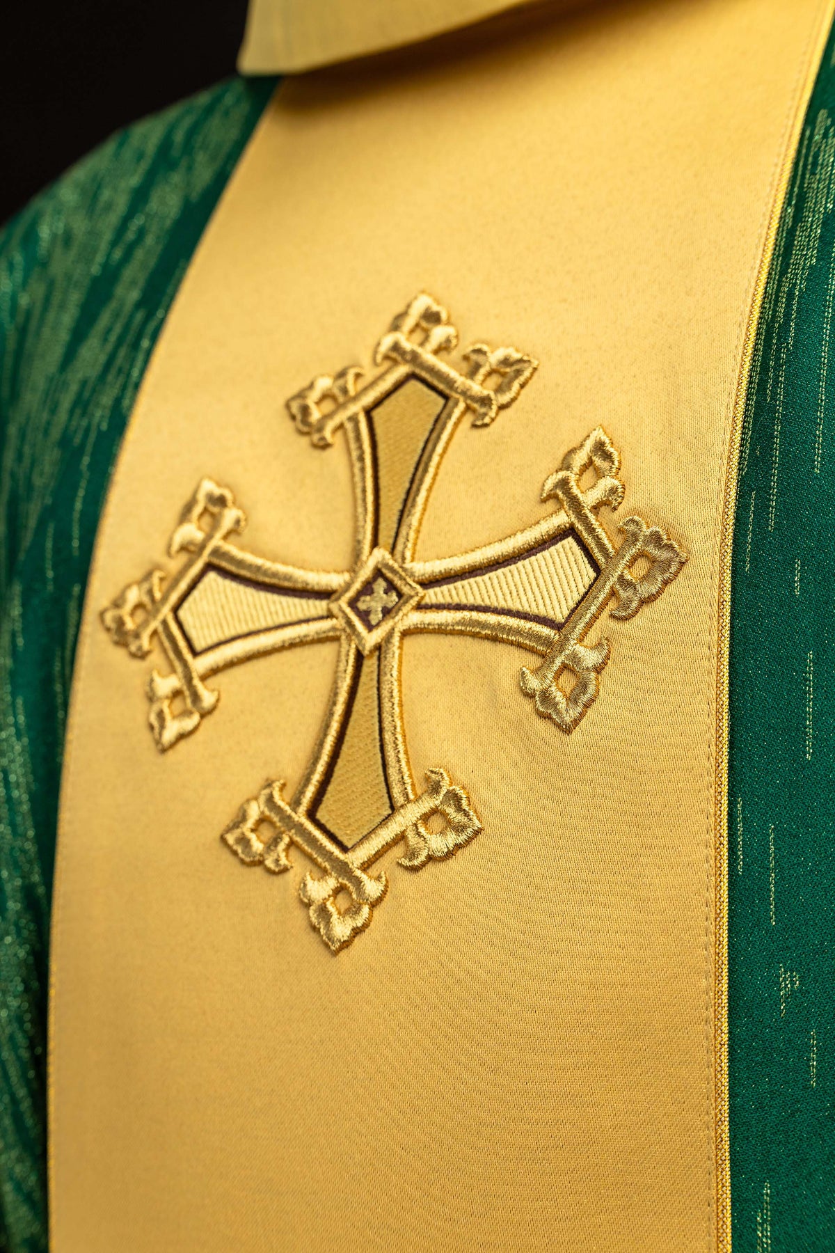 Casula verde com close-up da cruz bordada em dourado na faixa frontal