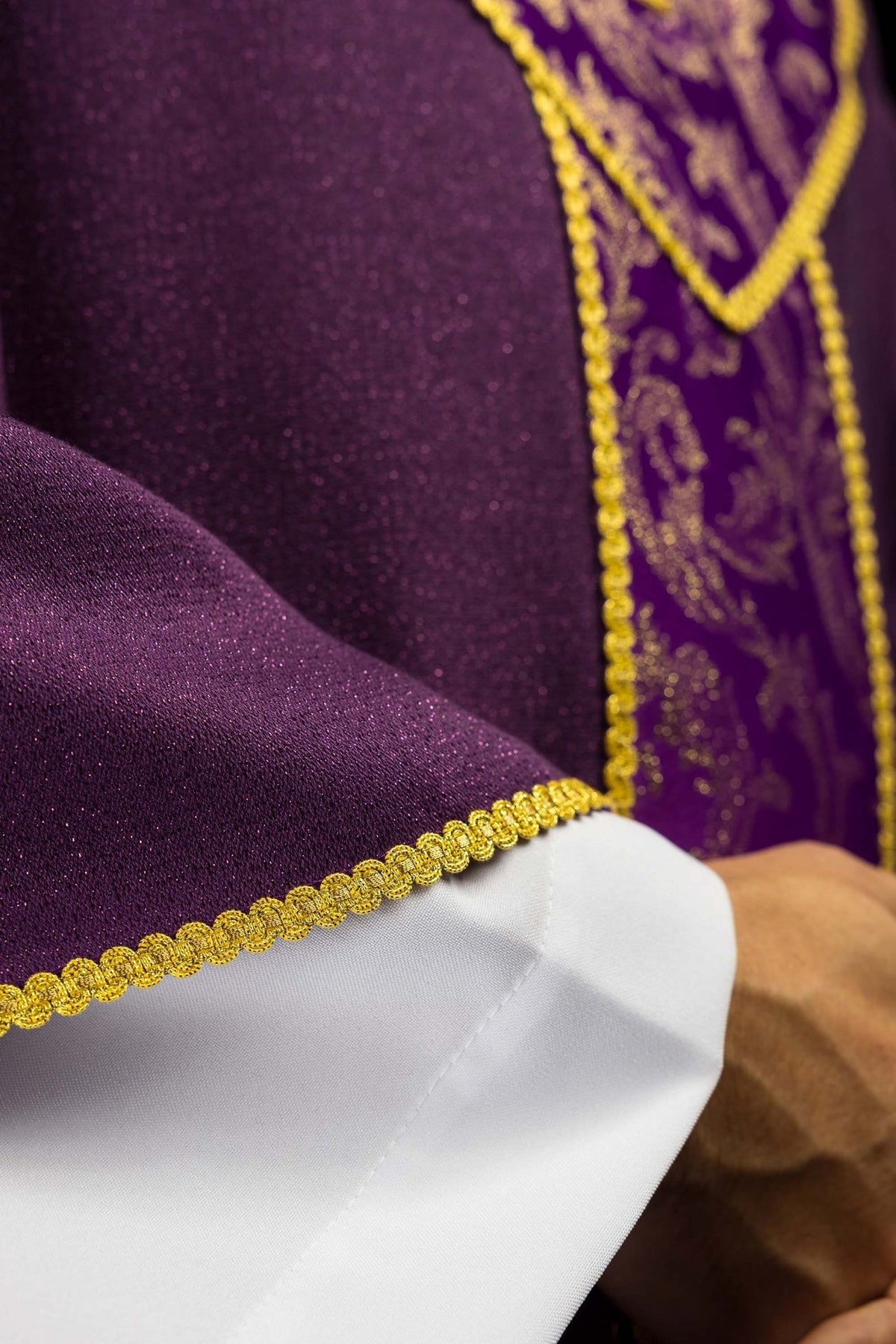 Casula roxa em detalhe, mostrando tecido liso, faixa jacquard e galão dourado