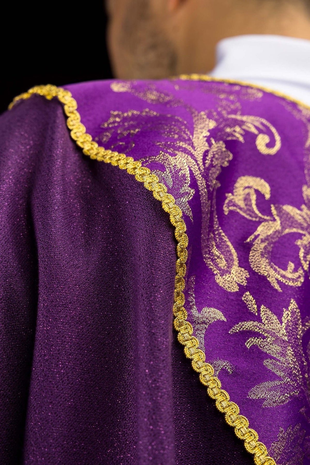 Casula roxa em detalhe da manga, com galão dourado e tecido jacquard