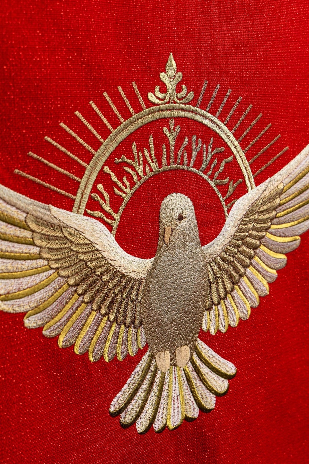 Toalha de ambão com close-up do bordado do Espírito Santo em dourado sobre tecido vermelho