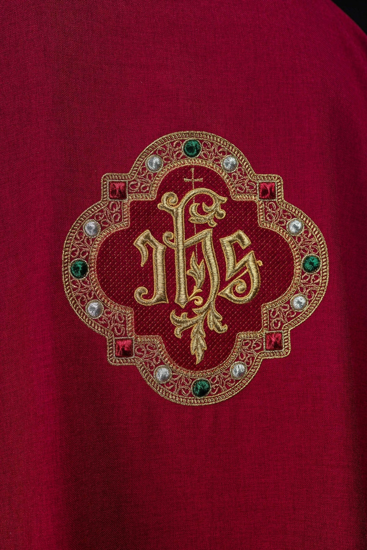 Dalmática vermelha, close-up do monograma IHS frontal com detalhes verdes, prateados e vermelhos