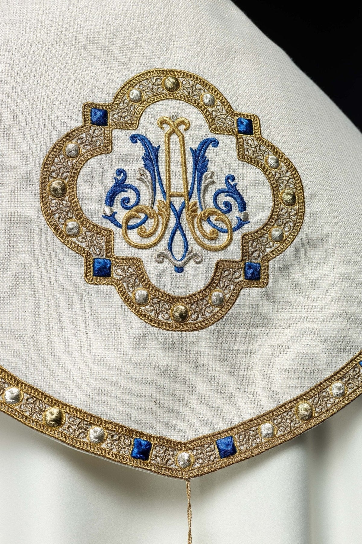 Capa de asperges com brasão mariano azul e dourado bordado em close-up