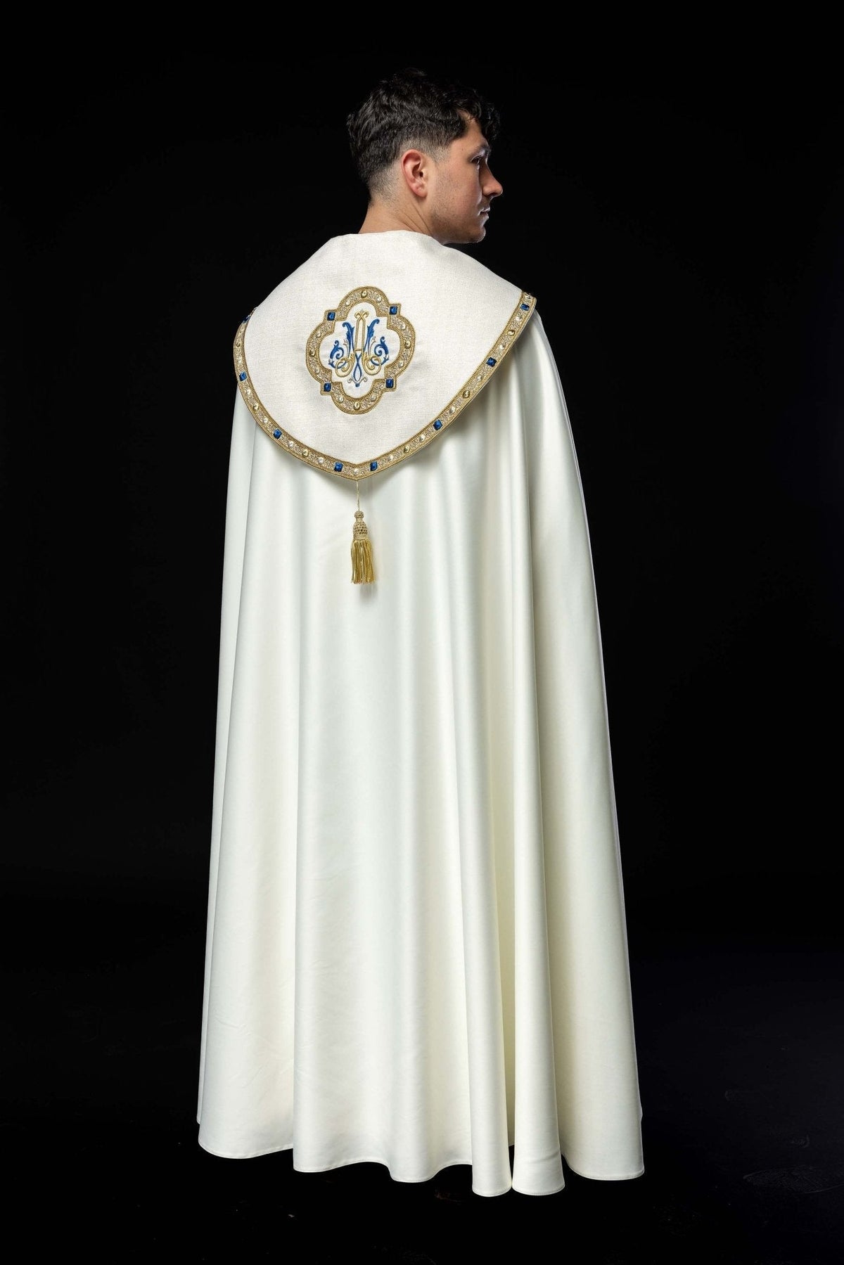 Capa de asperges branca vista posterior, com brasão mariano bordado e borla dourada