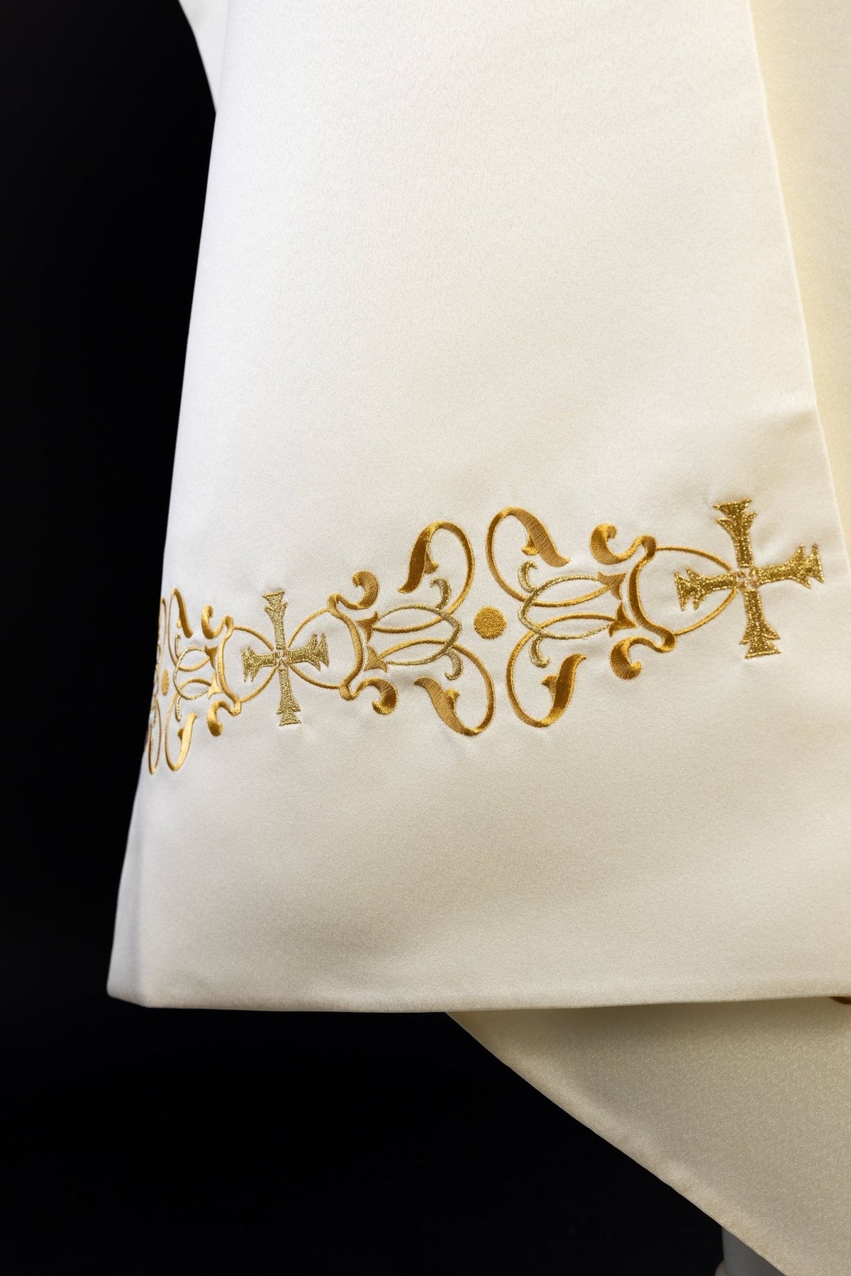 Véu marfim ecru em close-up, com bordado floral dourado e cruzes