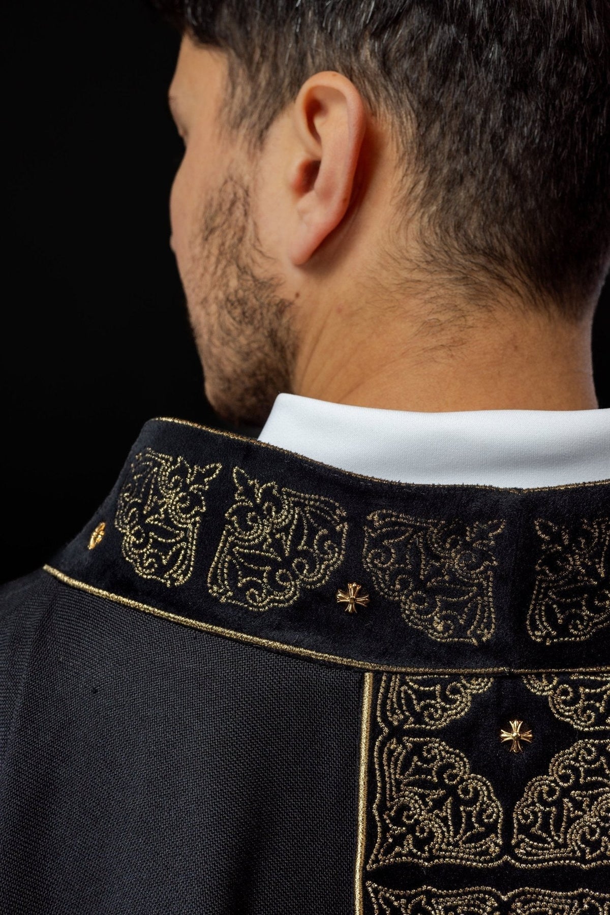 Casula preta bordada em dourado, close lateral da gola com motivos ornamentais