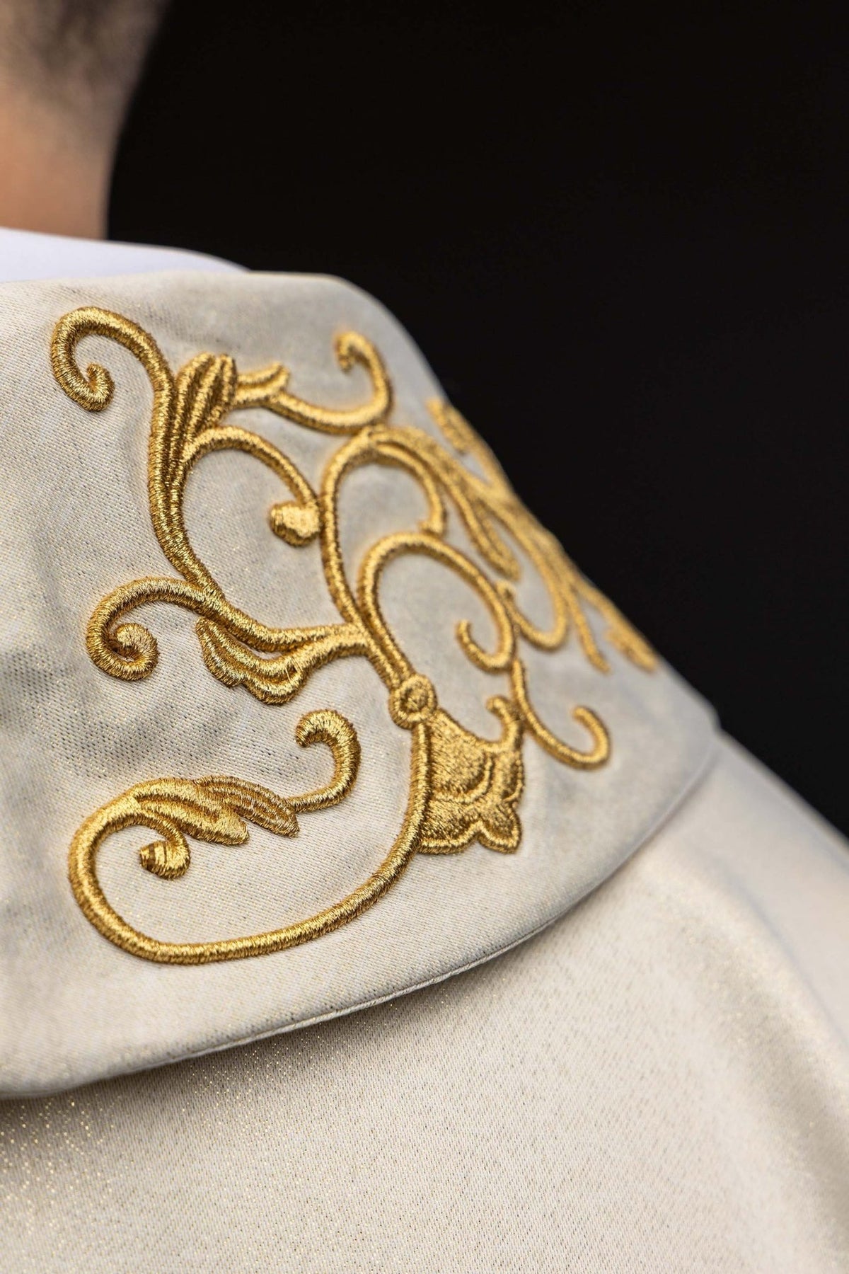 Casula com gola dobrada, close-up do bordado dourado em marfim ecru
