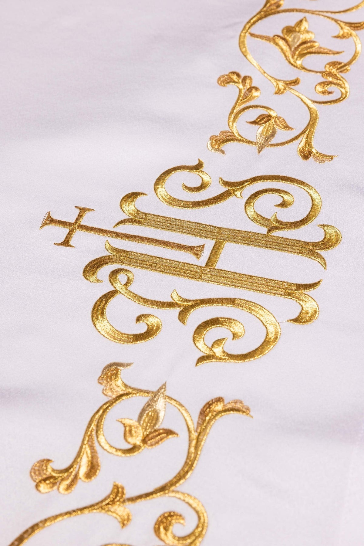 Toalha de altar com monograma IHS em close-up, bordado dourado sobre tecido branco