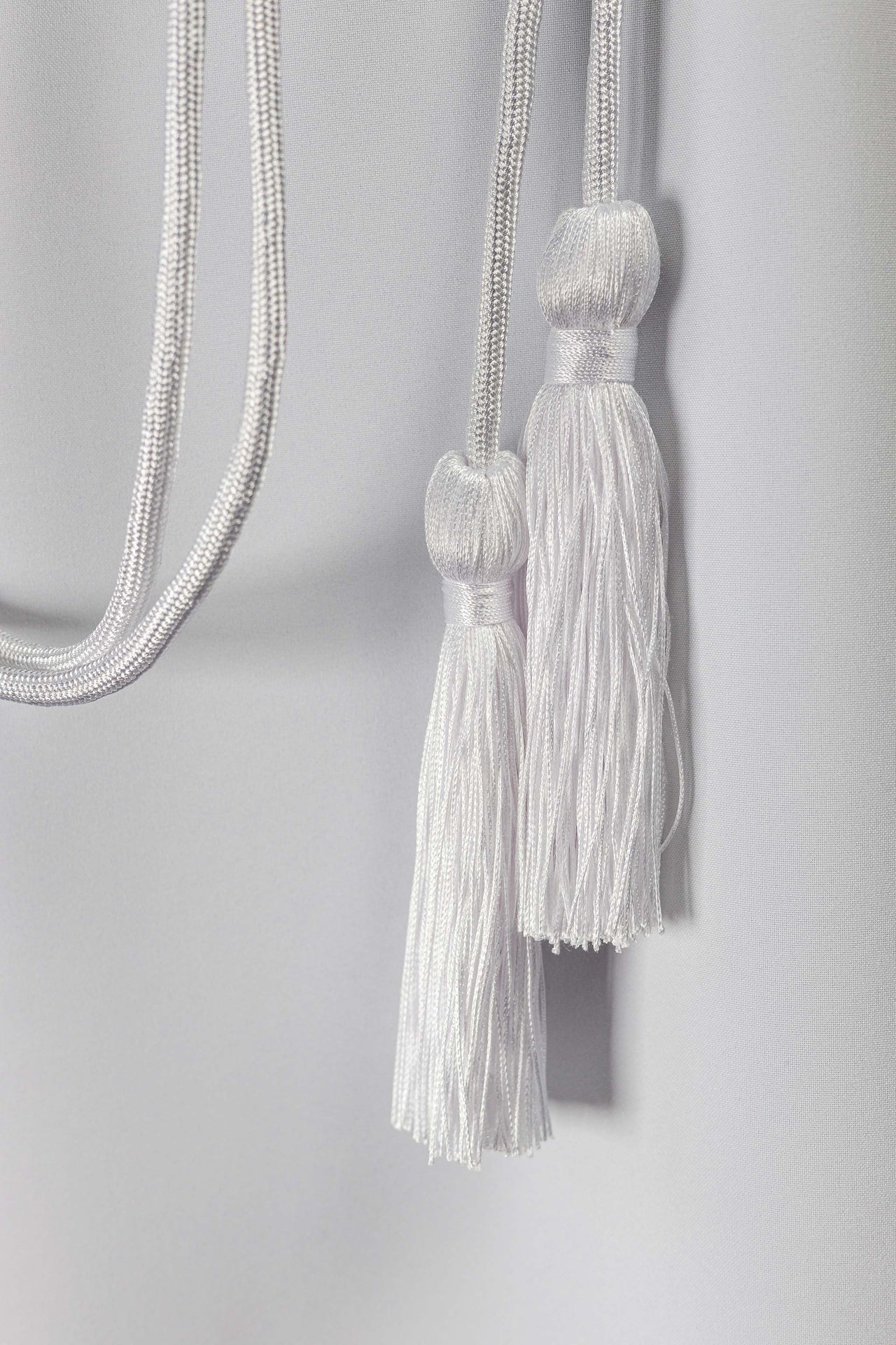 Detalhe do nó decorativo do cíngulo litúrgico branco na cintura da alva.