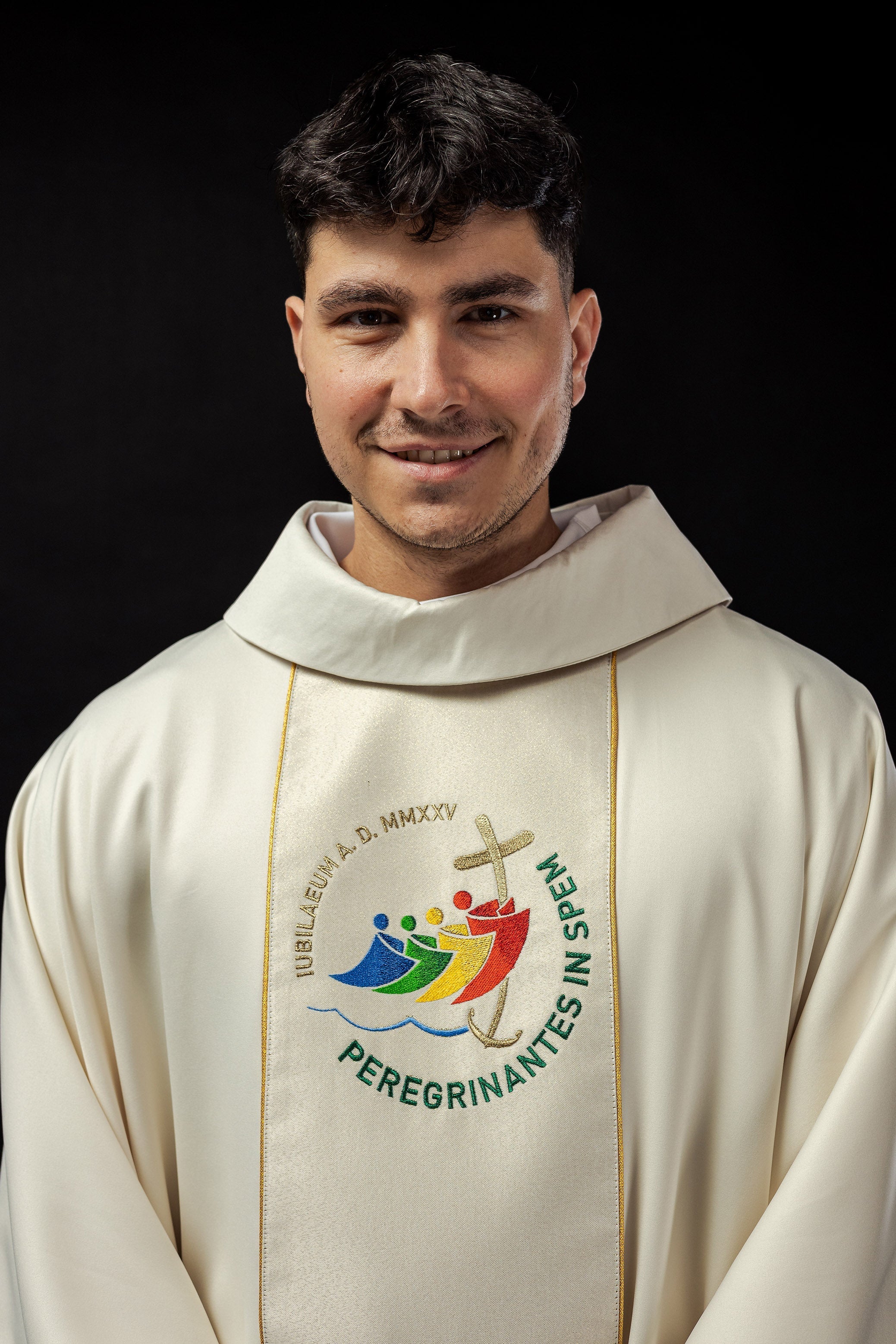 Casula creme com faixa bordada e logo do Jubileu Roma 2025