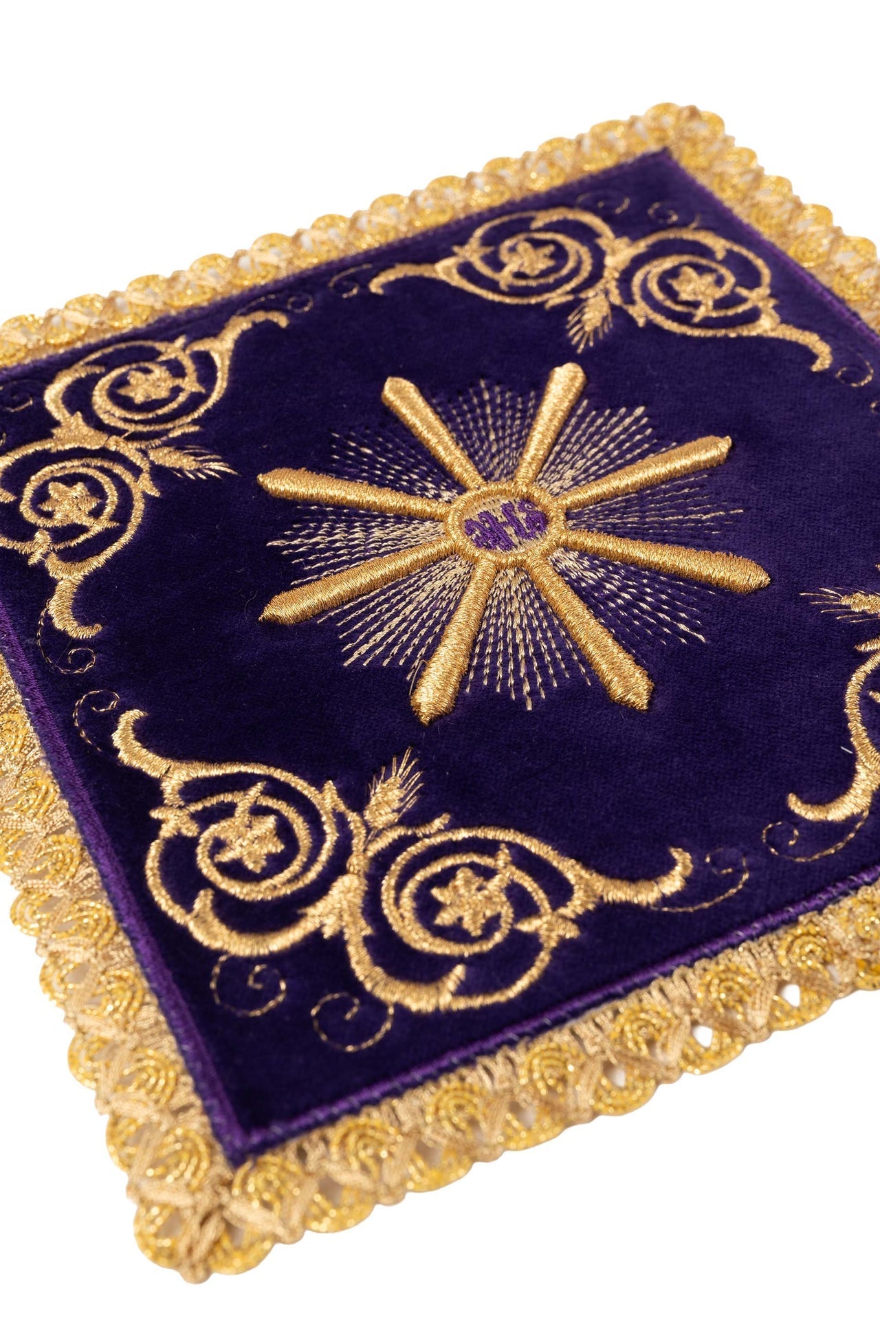 Conjunto de alfaias litúrgicas roxas: pala de veludo com bordado do sol eucarístico IHS sobre um cálice dourado, corporal, sanguíneo e manutérgio brancos com cruzes.