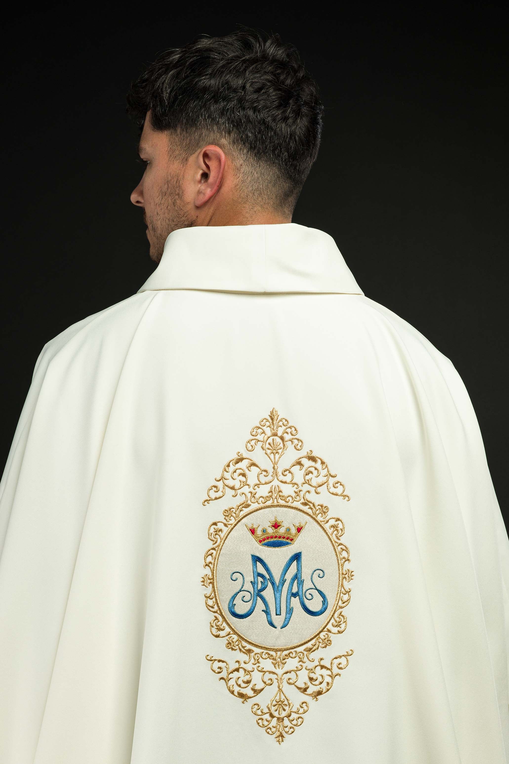 Casula com motivo mariano e bordado dourado, brasão mariano em dourado e azul, coroa dourada, gola alta.