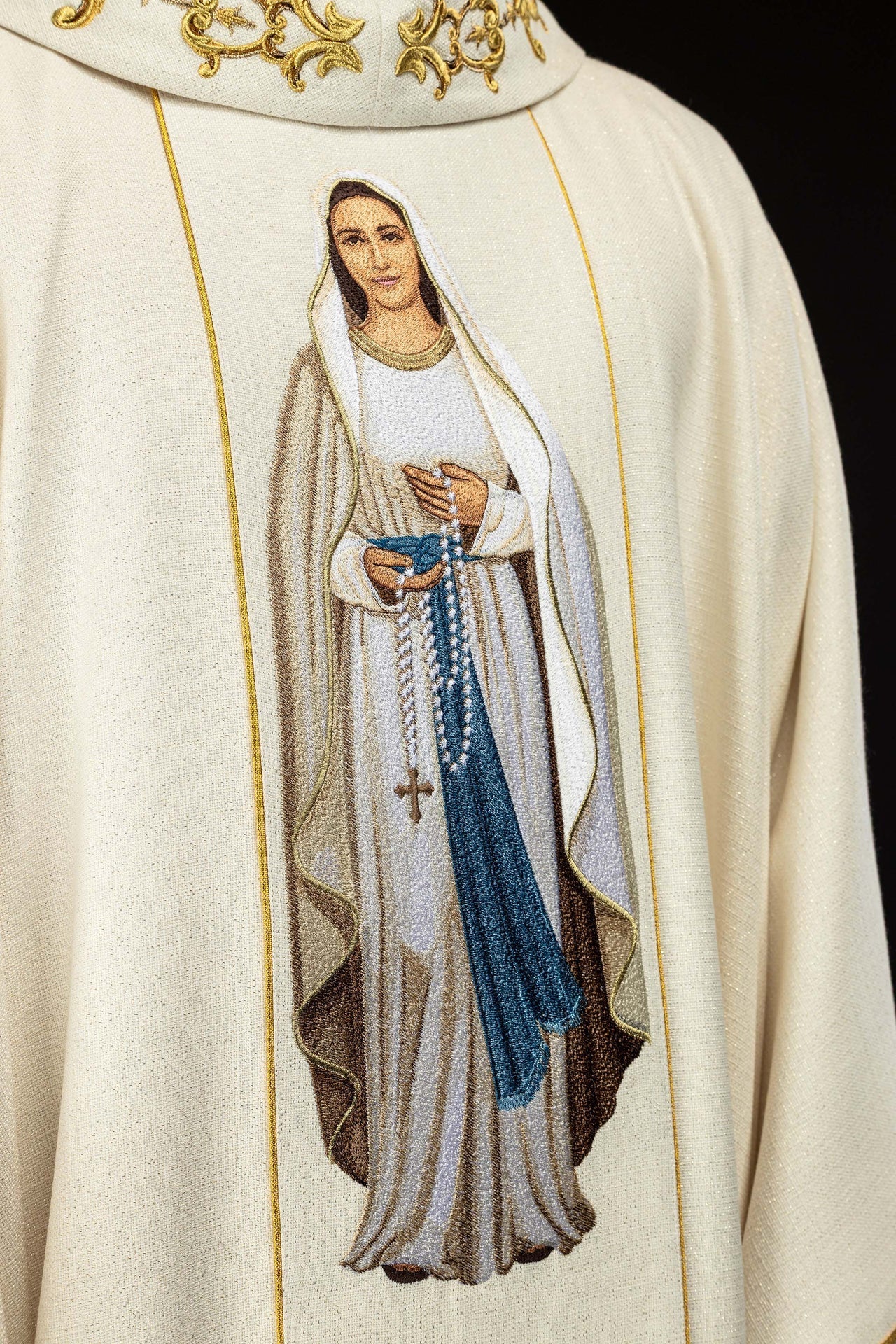 Casula creme com bordado de Nossa Senhora do Rosário e detalhes dourados.