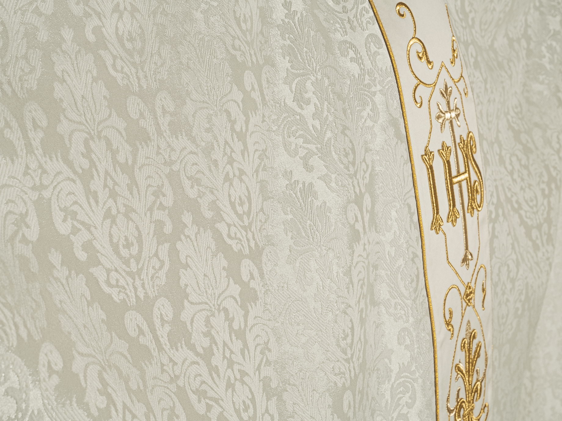 Casula creme bordada em tecido decorativo com símbolo IHS