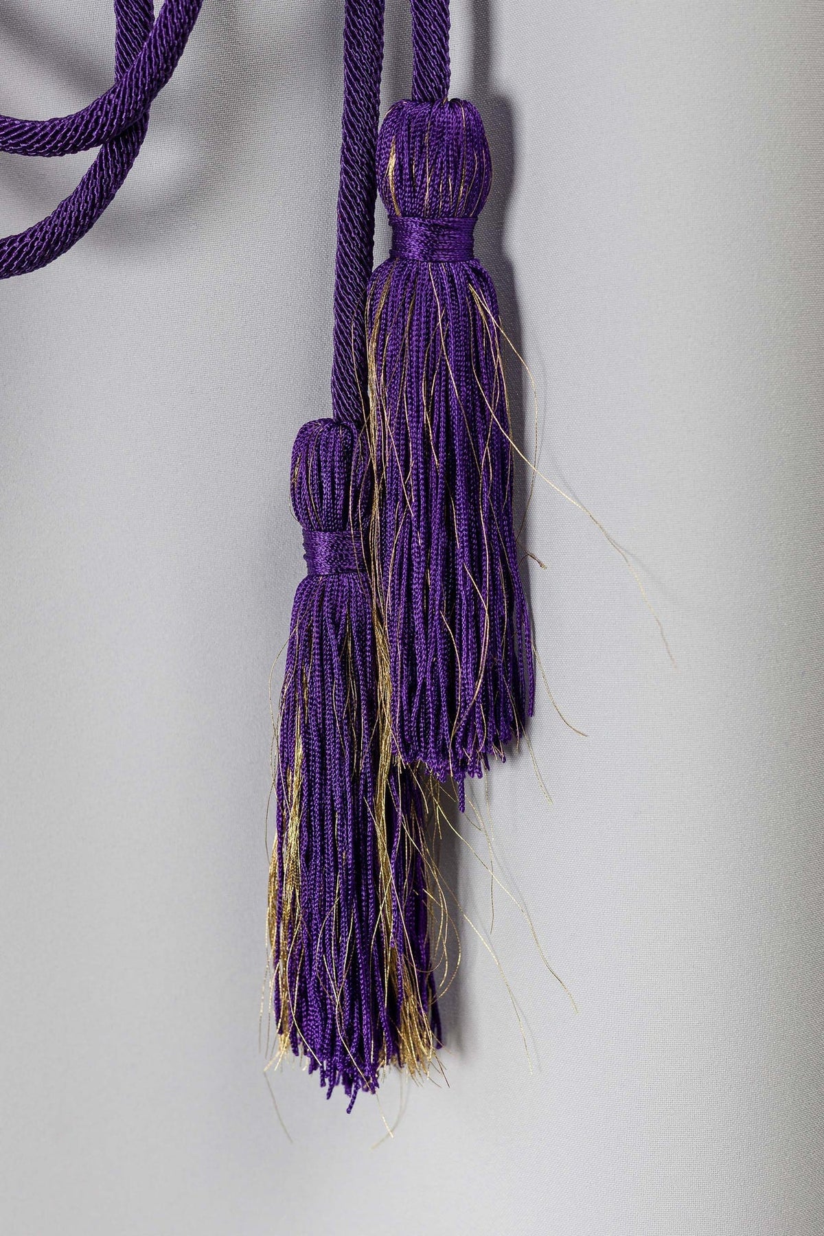 Cíngulo litúrgico roxo com close-up das borlas roxas e fios dourados