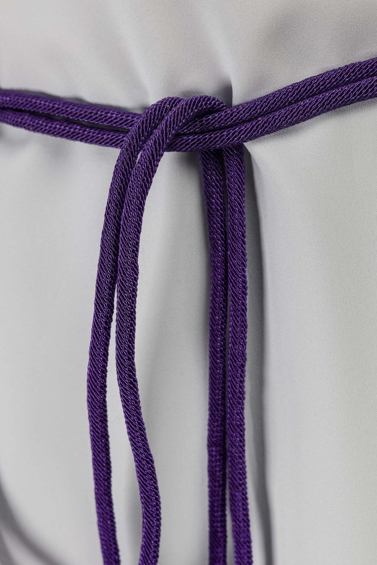Cíngulo litúrgico roxo em close-up do nó central e cordões pendentes
