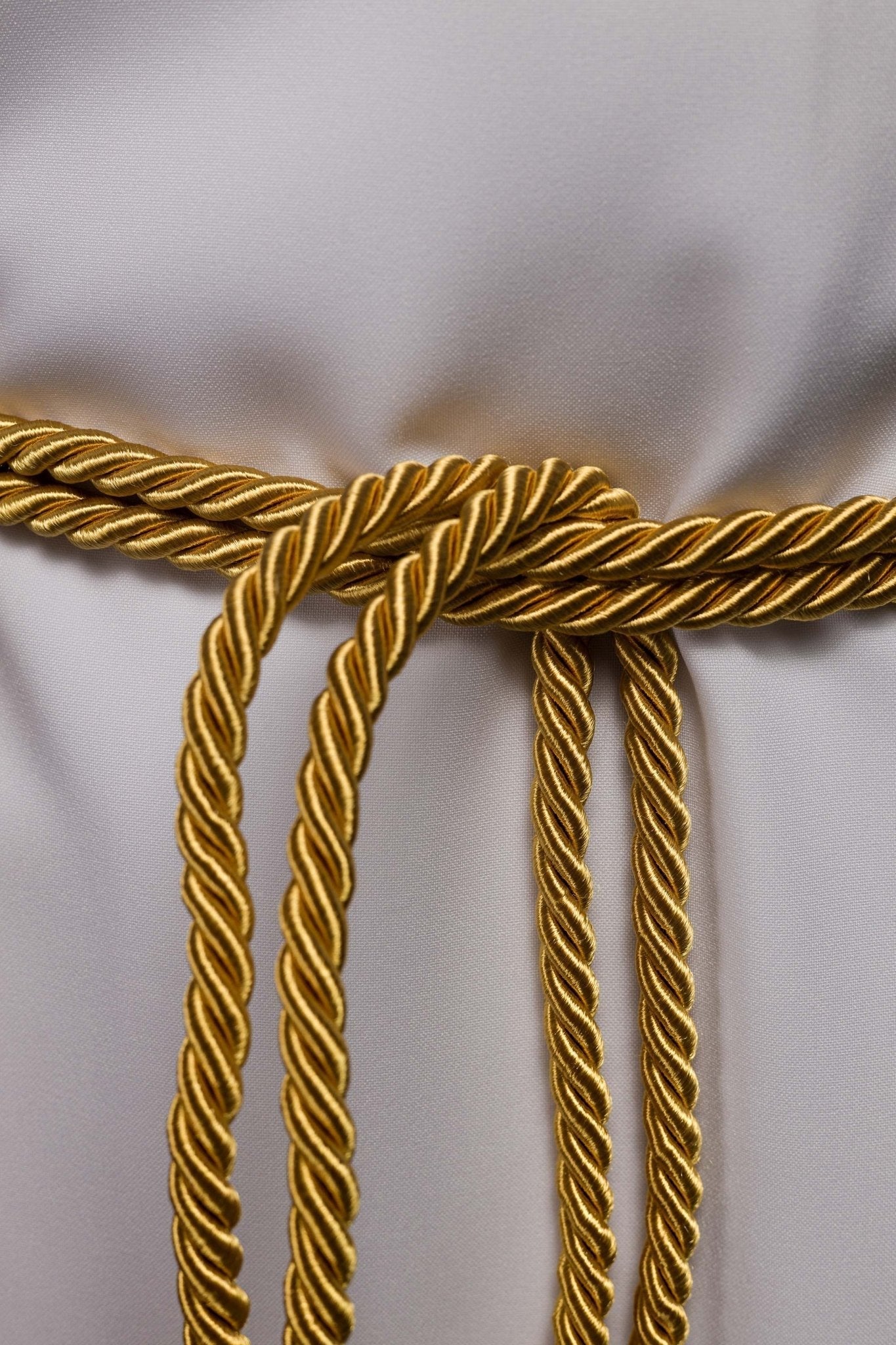 Cíngulo litúrgico dourado amarrado em uma alva branca
