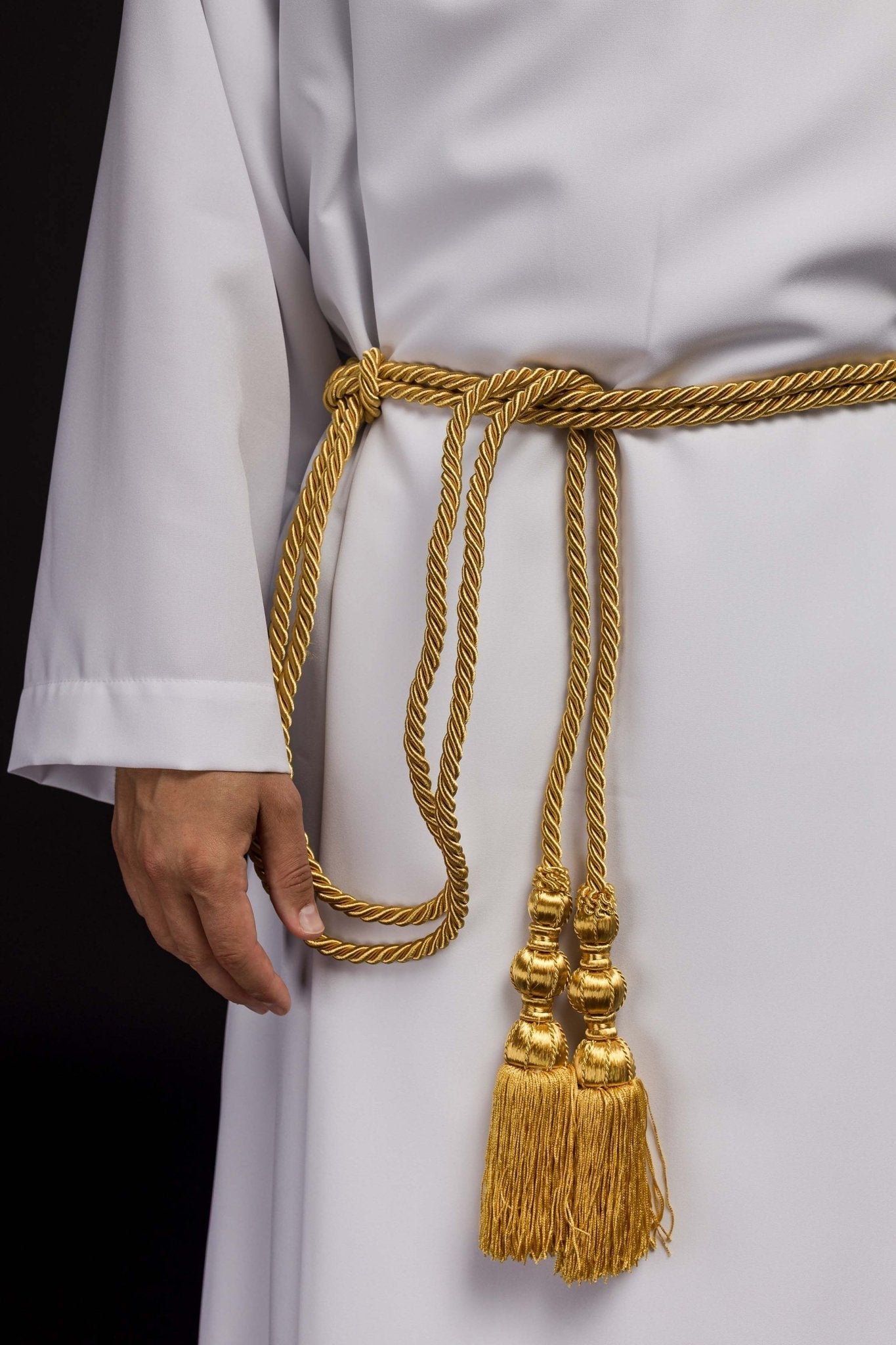 Cíngulo litúrgico dourado amarrado em uma alva branca