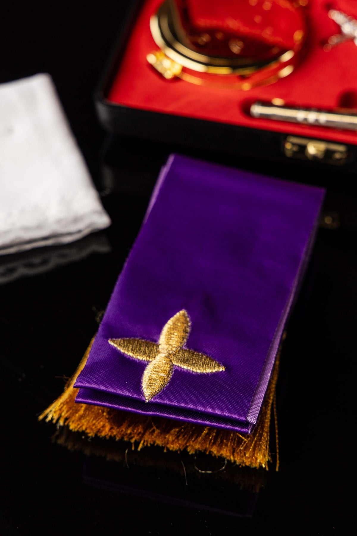 Faixa roxa da bolsa litúrgica com bordado dourado em forma de cruz e franjas douradas