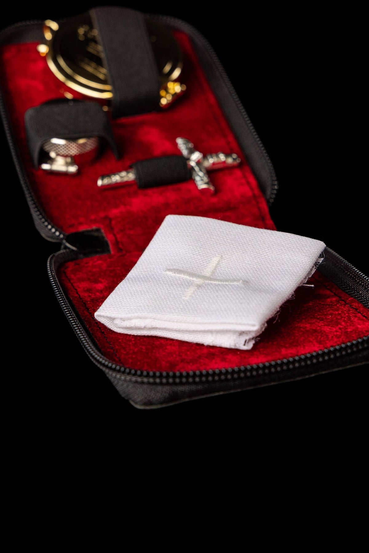 Bolsa litúrgica aberta com corporal branco e acessórios metálicos