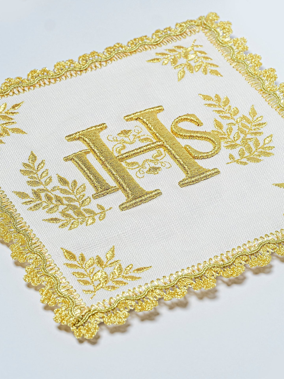 Conjunto de alfaias litúrgicas com close-up do bordado IHS dourado e acabamento ornamentado