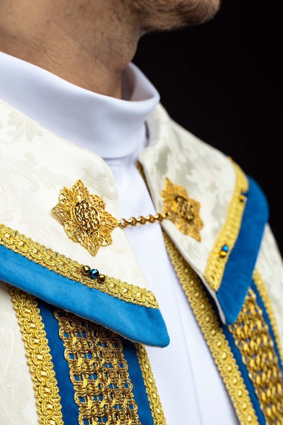 Capa de asperges litúrgica mariana, close-up do alamar dourado e das pedras azuis