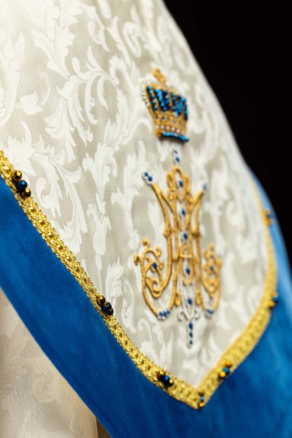 Capa de asperges litúrgica mariana, detalhe do símbolo mariano bordado com coroa e pedras