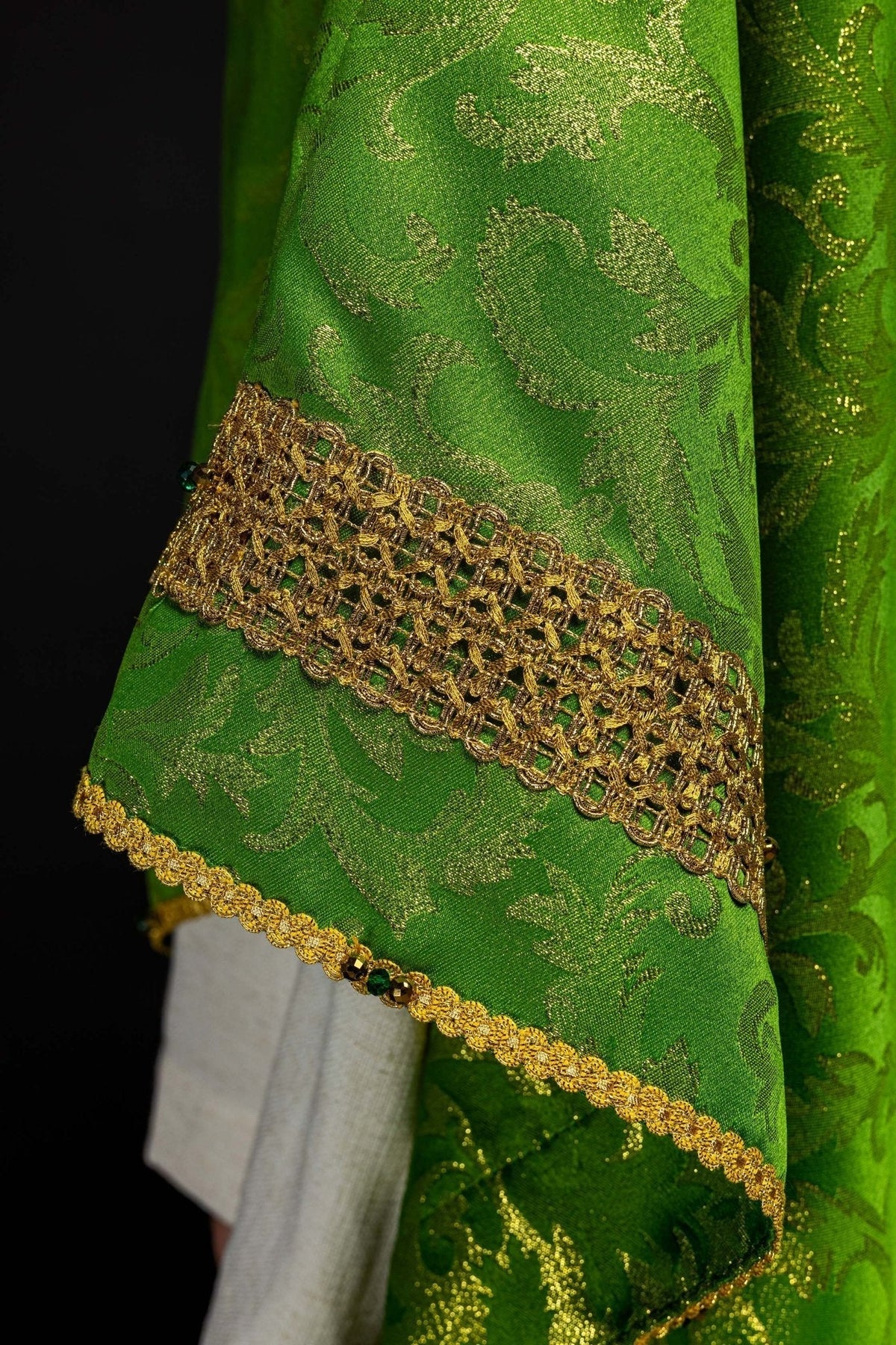 Casula verde com pedras naturais, detalhe da manga com galão dourado e acabamento decorativo