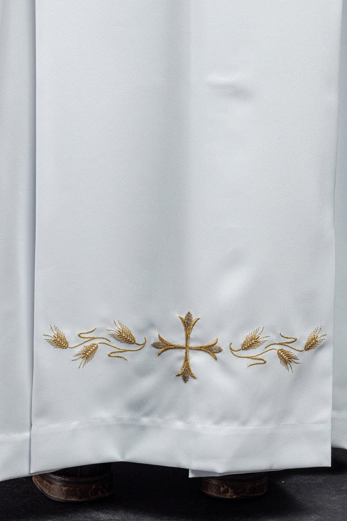Alva sacerdotal branca, close-up do bordado dourado de cruz e espigas na barra