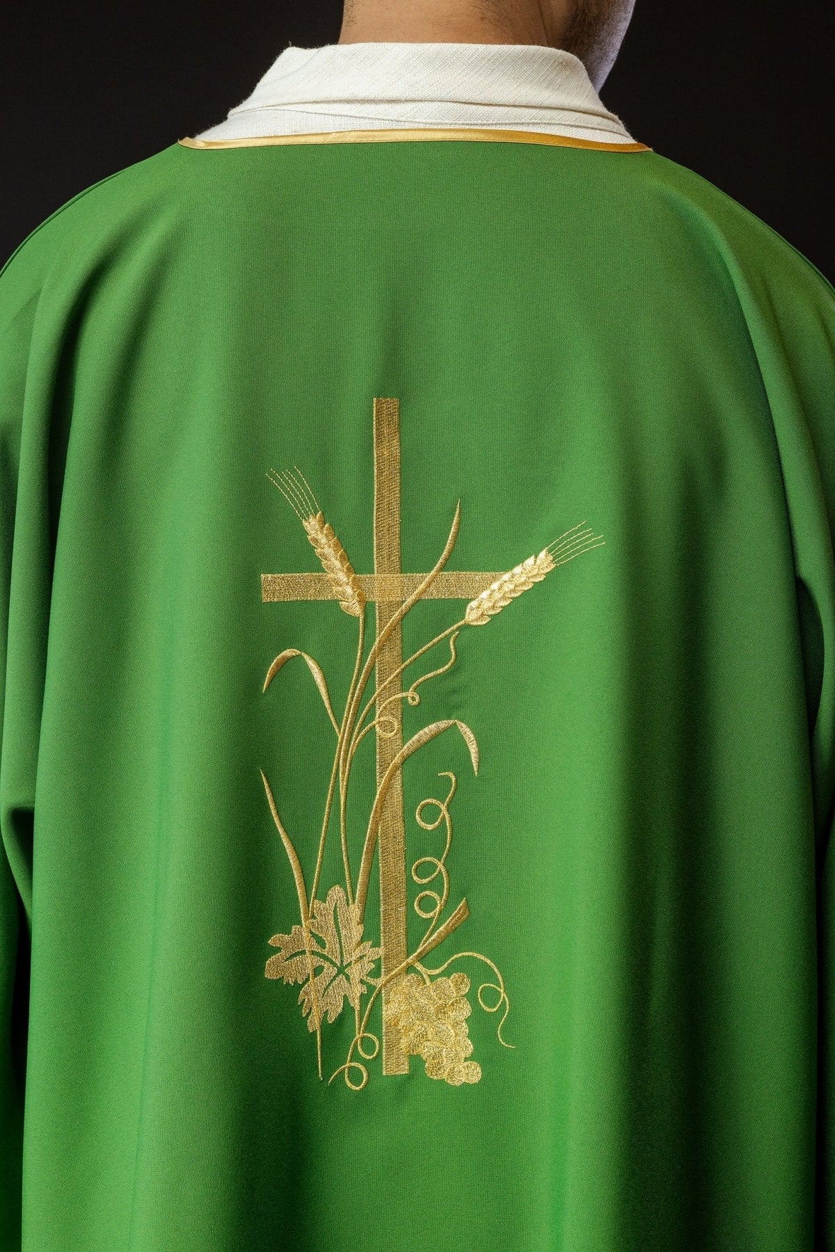 Dalmática verde com bordado dourado da cruz Pax vista de costas, com cruz e motivos de trigo e uvas