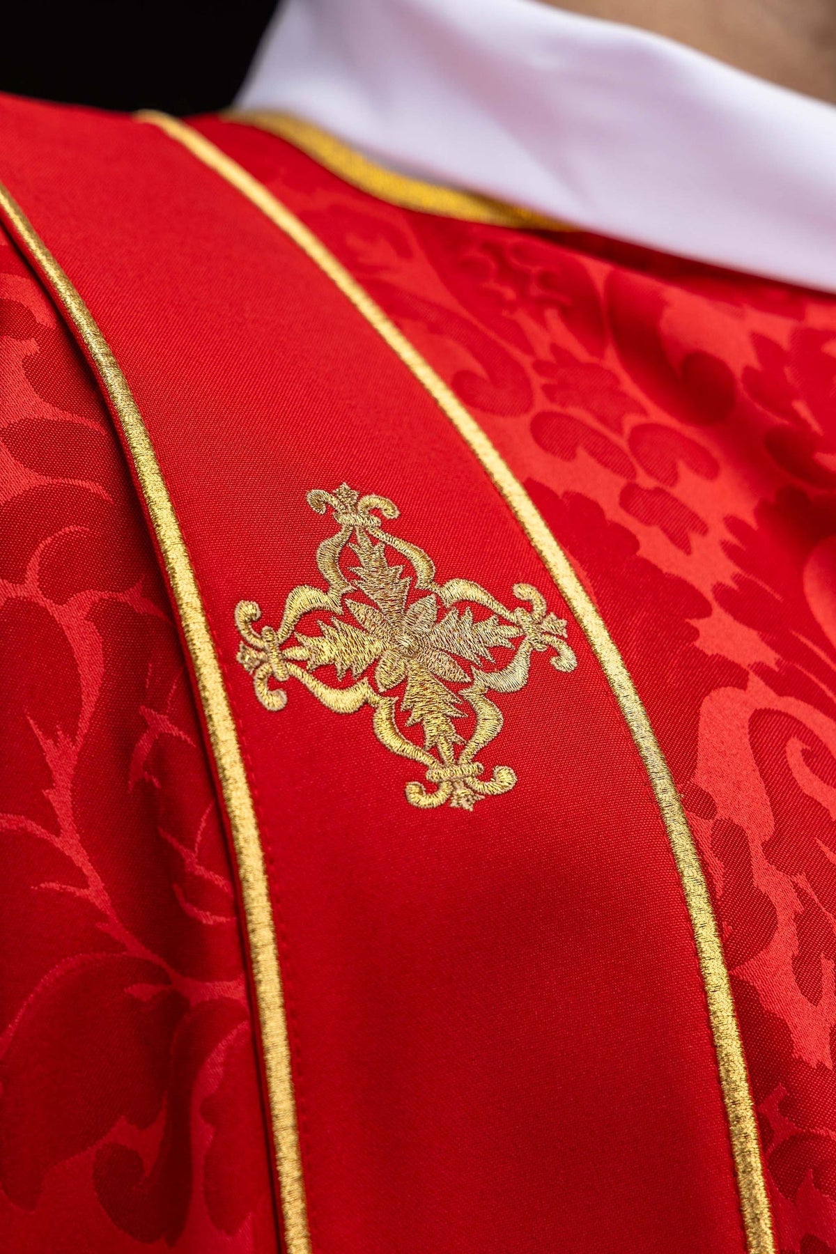 Dalmática vermelha em jacquard, close-up da faixa com cruz bordada dourada