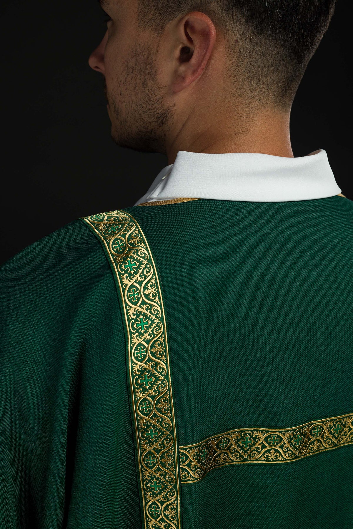 Dalmática verde vista de trás, com galões jacquard dourados e faixa horizontal