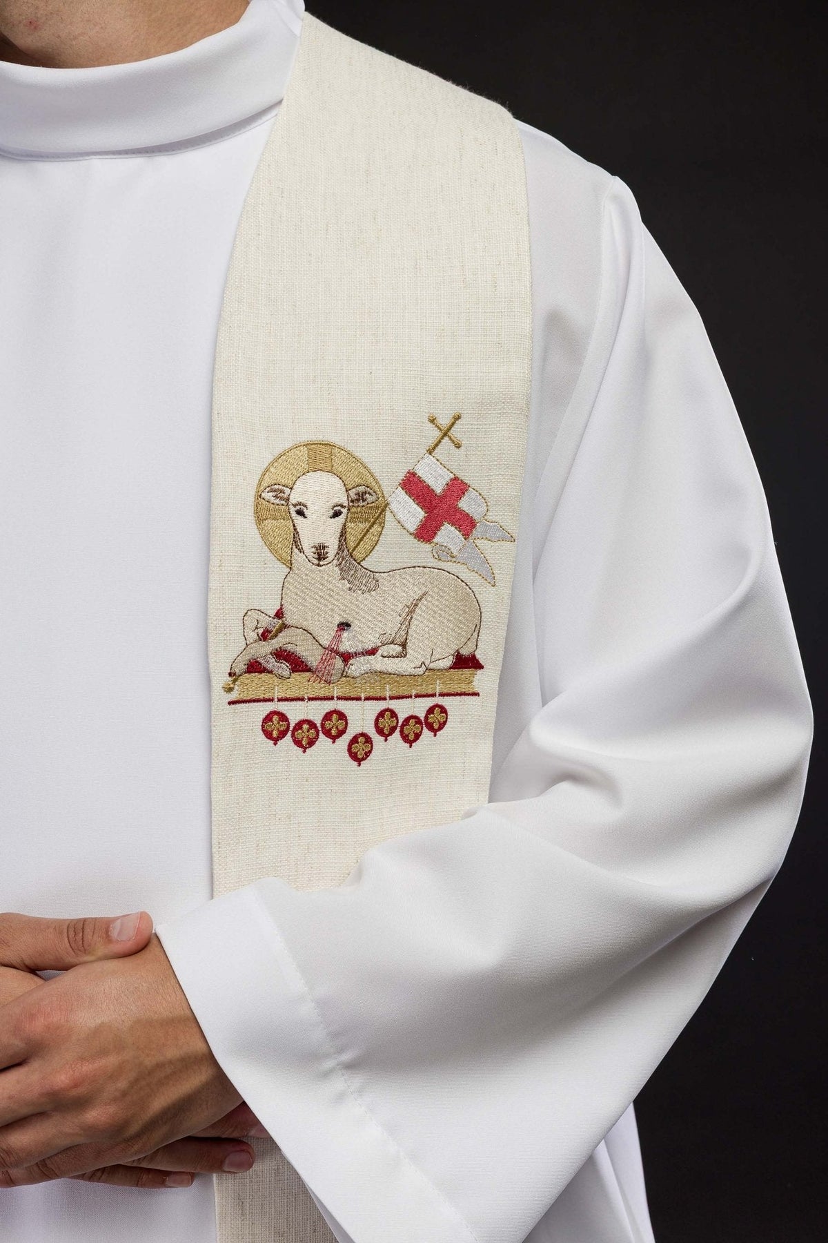 Estola pascal marfim em close-up, com bordado do Cordeiro de Deus, estandarte e medalhões vermelhos
