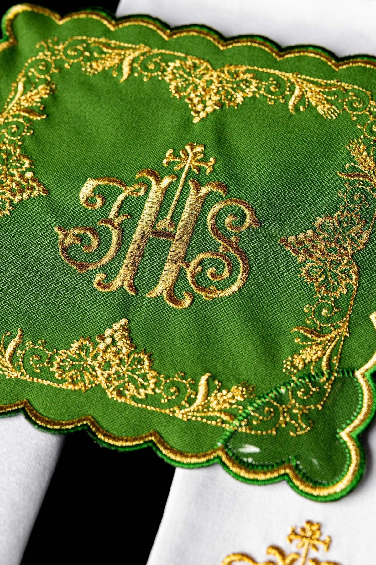 Conjunto de alfaias litúrgicas verde em close-up, com monograma IHS e bordado floral dourado