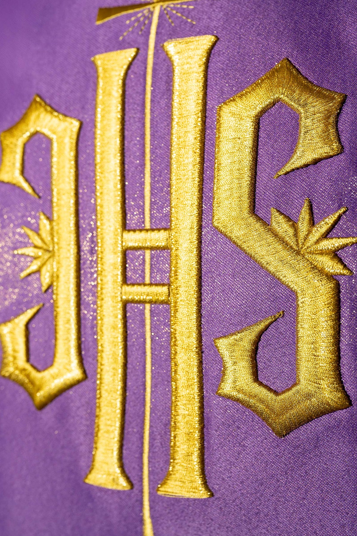 Casula roxa com close-up do bordado dourado IHS