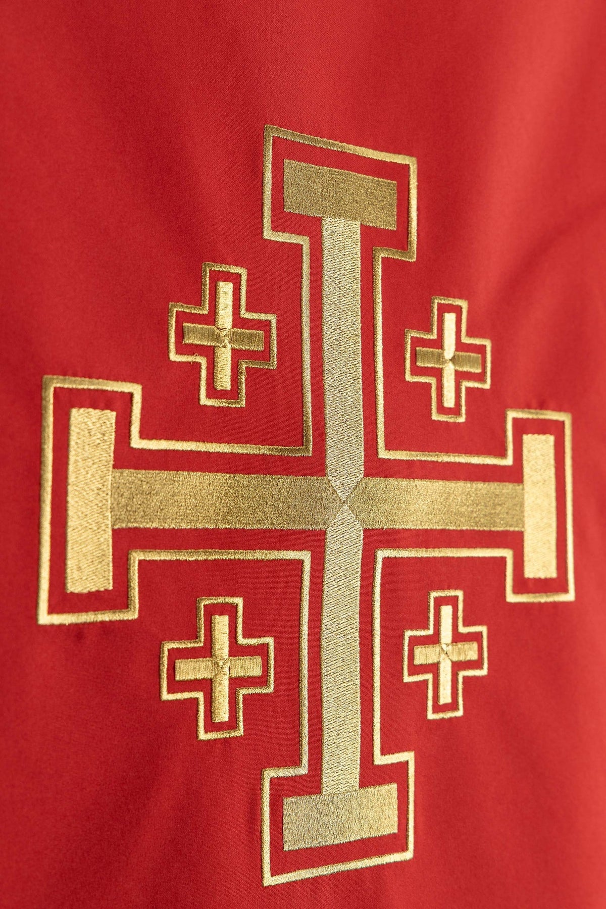 Toalha de ambão vermelha em close-up do bordado dourado da Cruz de Jerusalém
