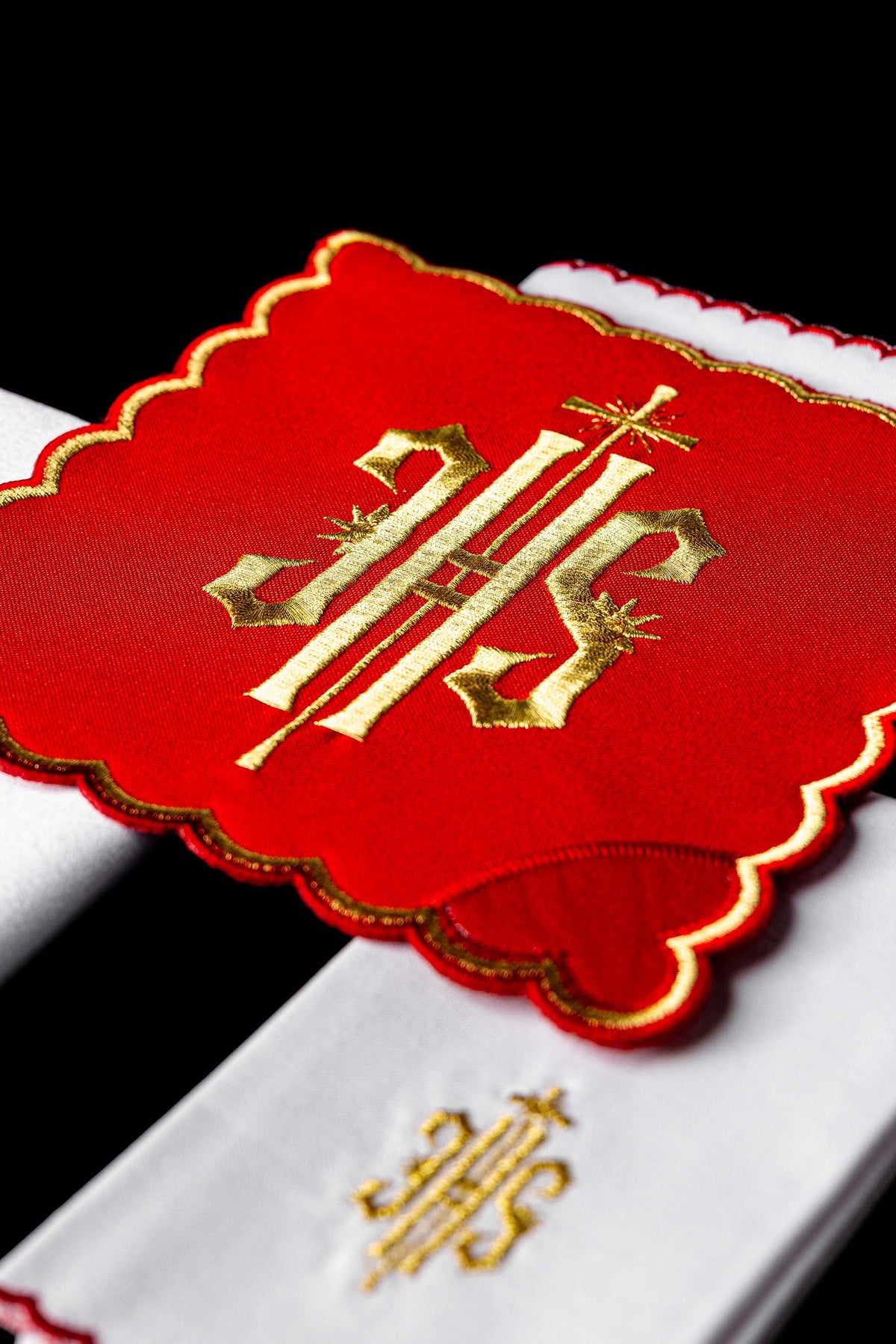 Alfaias litúrgicas com close-up do painel vermelho e IHS dourado