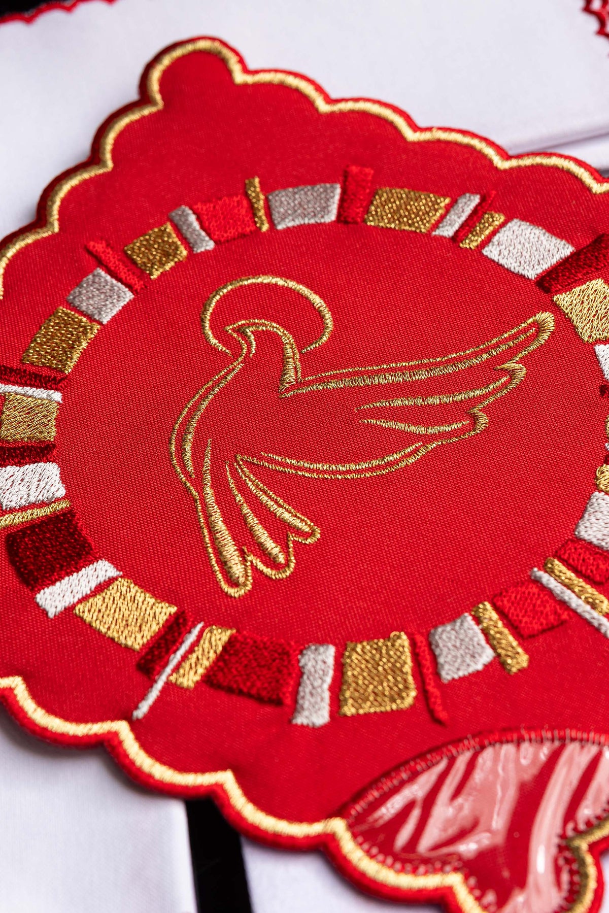 Alfaias litúrgicas vermelhas com detalhe do Espírito Santo bordado em dourado