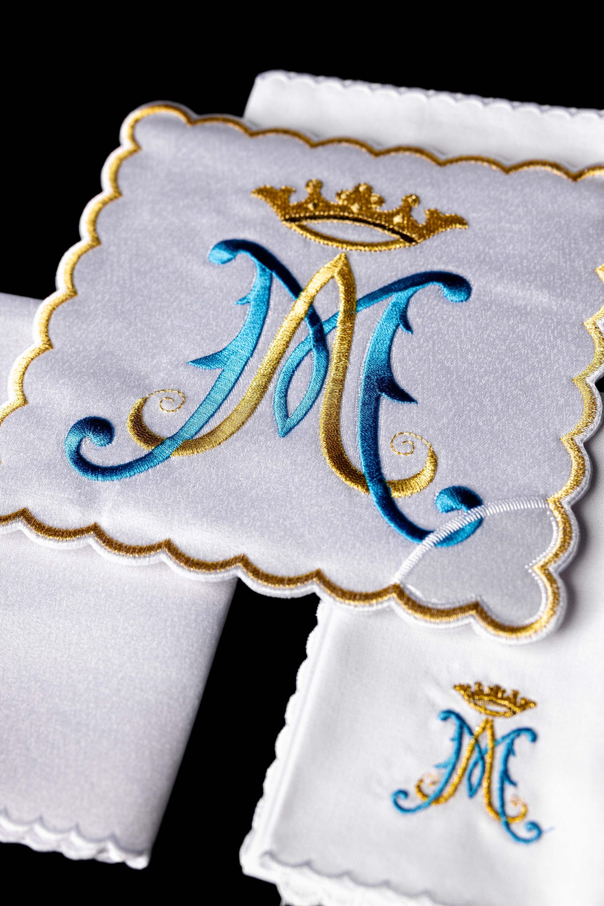 Conjunto de alfaias com detalhe do monograma mariano bordado em azul e dourado