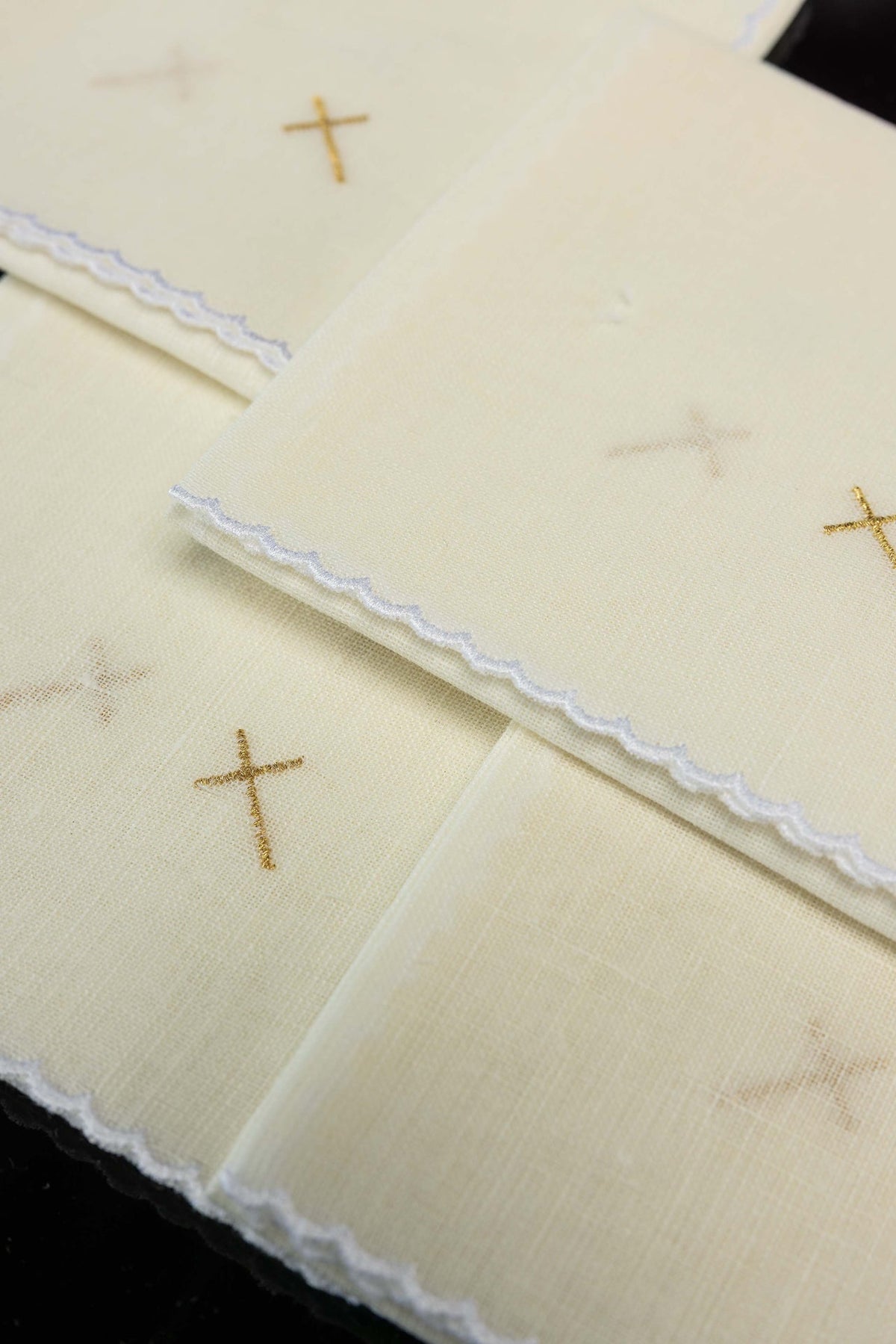 Corporais em marfim ecru com cruz dourada bordada, vista aproximada