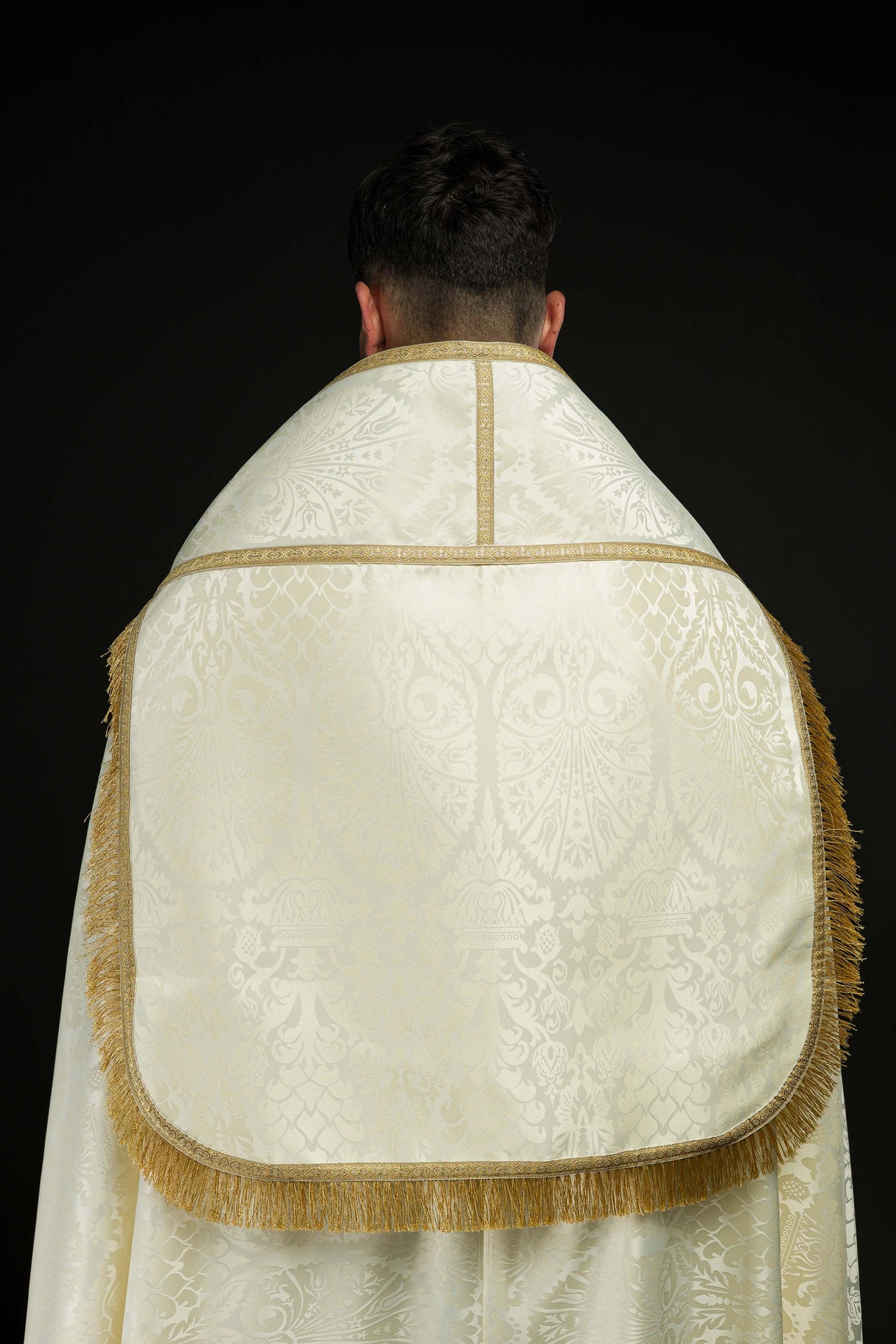 Capa de asperges creme vista de trás, com pala arredondada, franjas douradas e galão