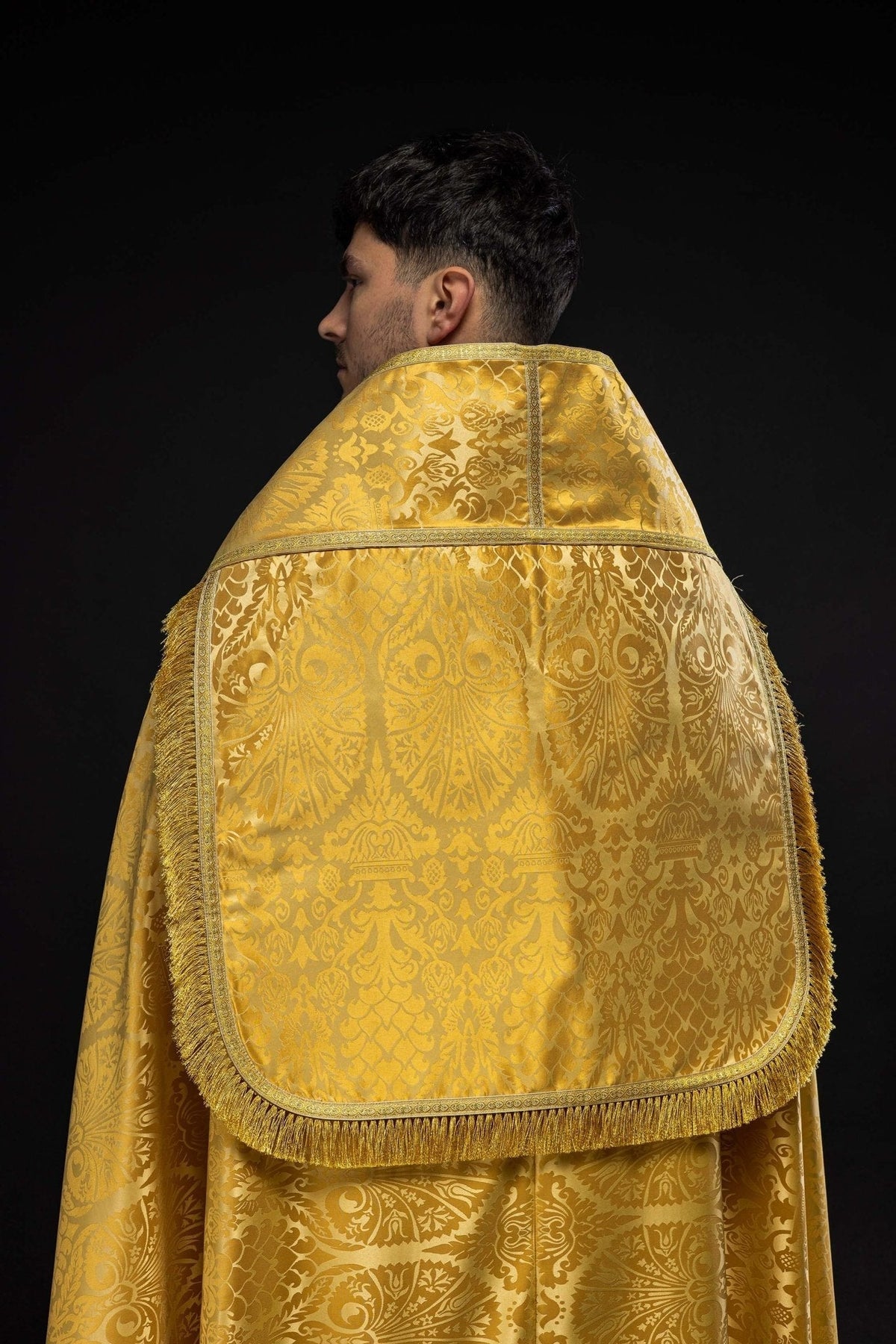 Capa de asperges dourada em jacquard, vista posterior com pala arredondada e franjas