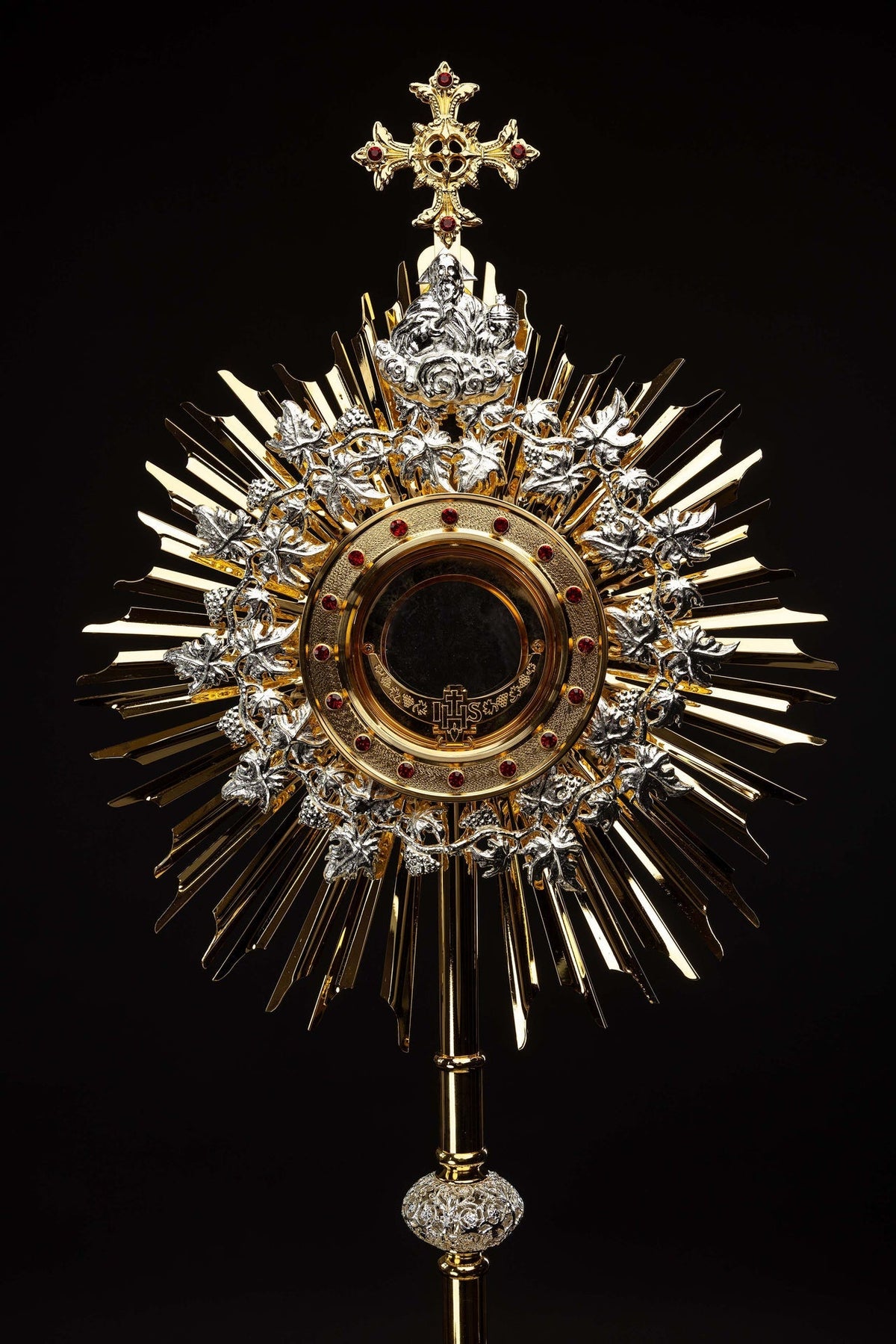 Ostensório dourado com rubis, close-up da base com folhas prateadas e pedras vermelhas