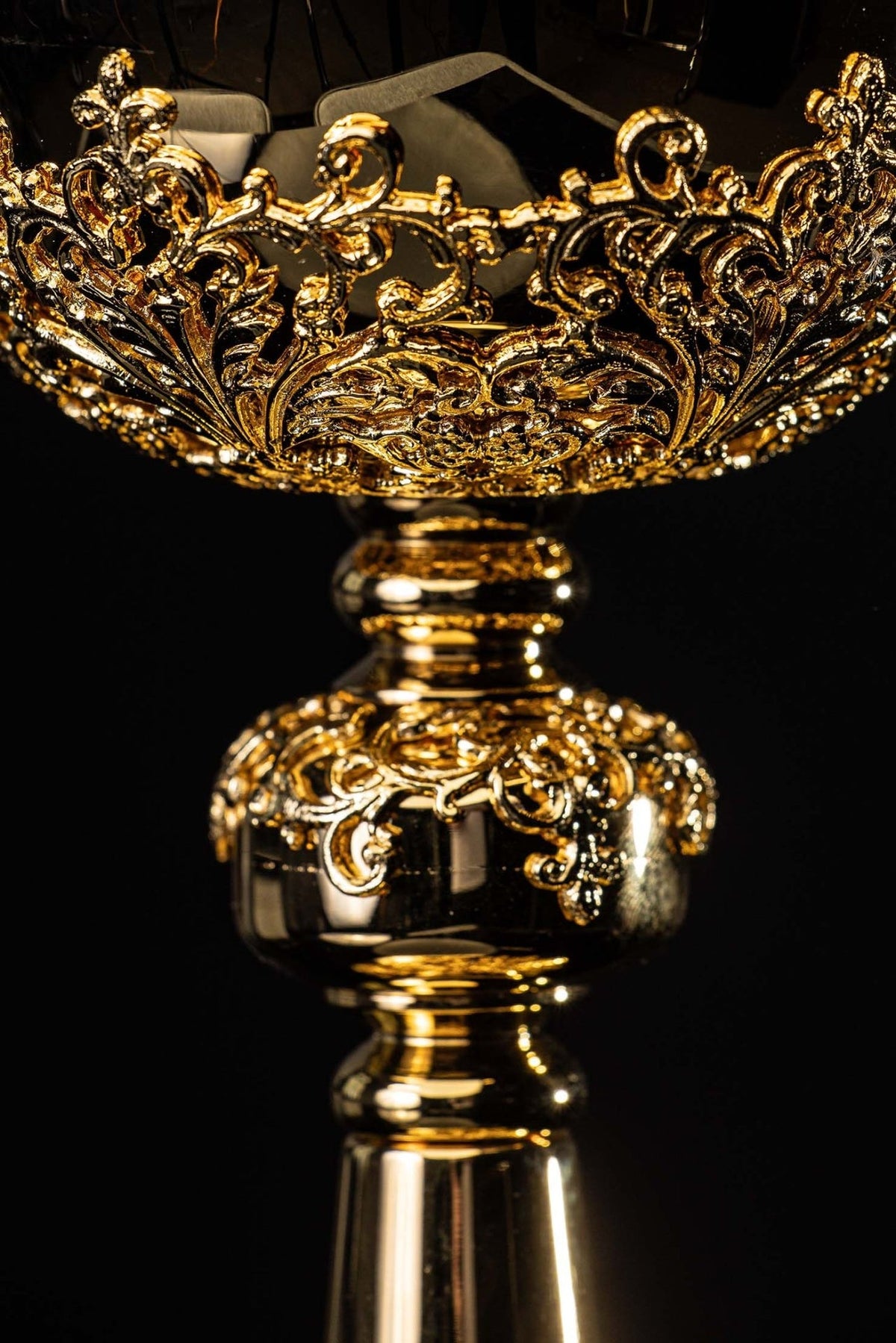 Âmbula dourada em close-up da faixa ornamental da copa, com arabescos em relevo
