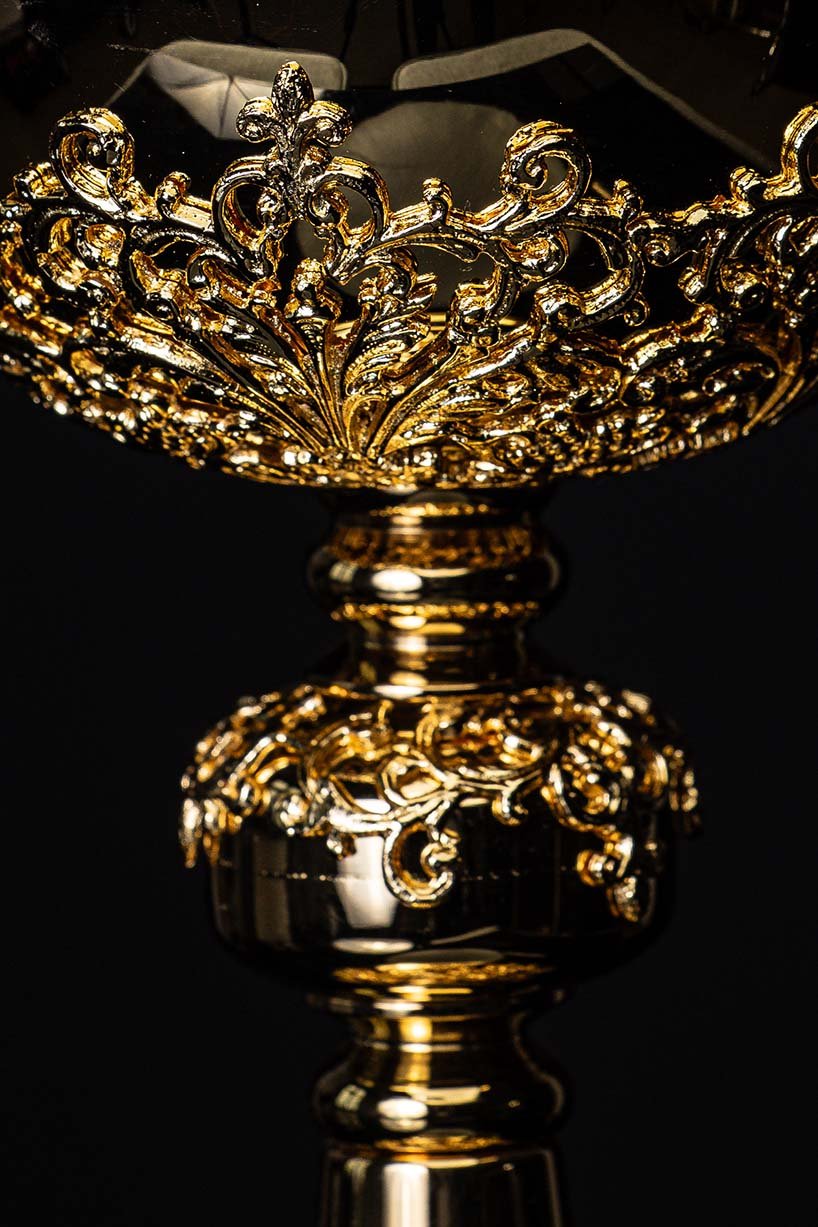 Âmbula dourada em close-up lateral da borda ornamental com arabescos e acabamento trabalhado