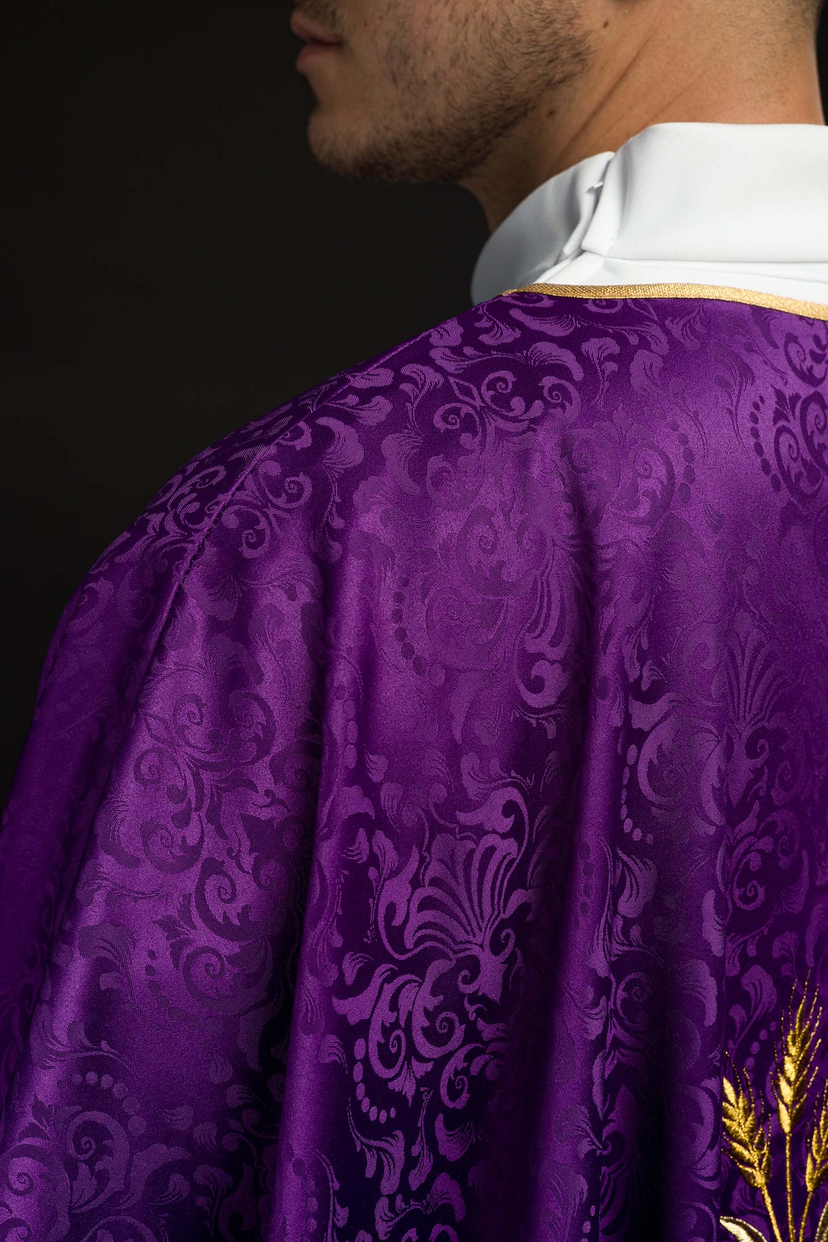 Casula roxa em detalhe lateral do tecido jacquard e acabamento dourado