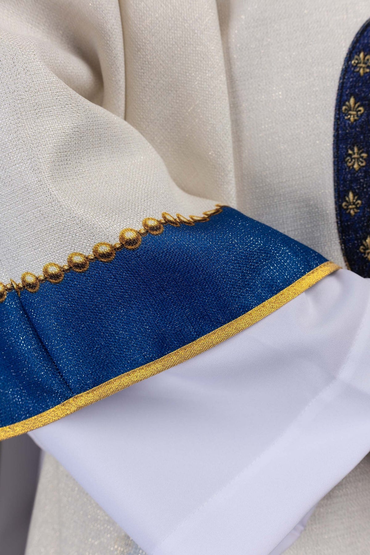 Casula com detalhe da faixa azul, acabamento dourado e tecido marfim ecru